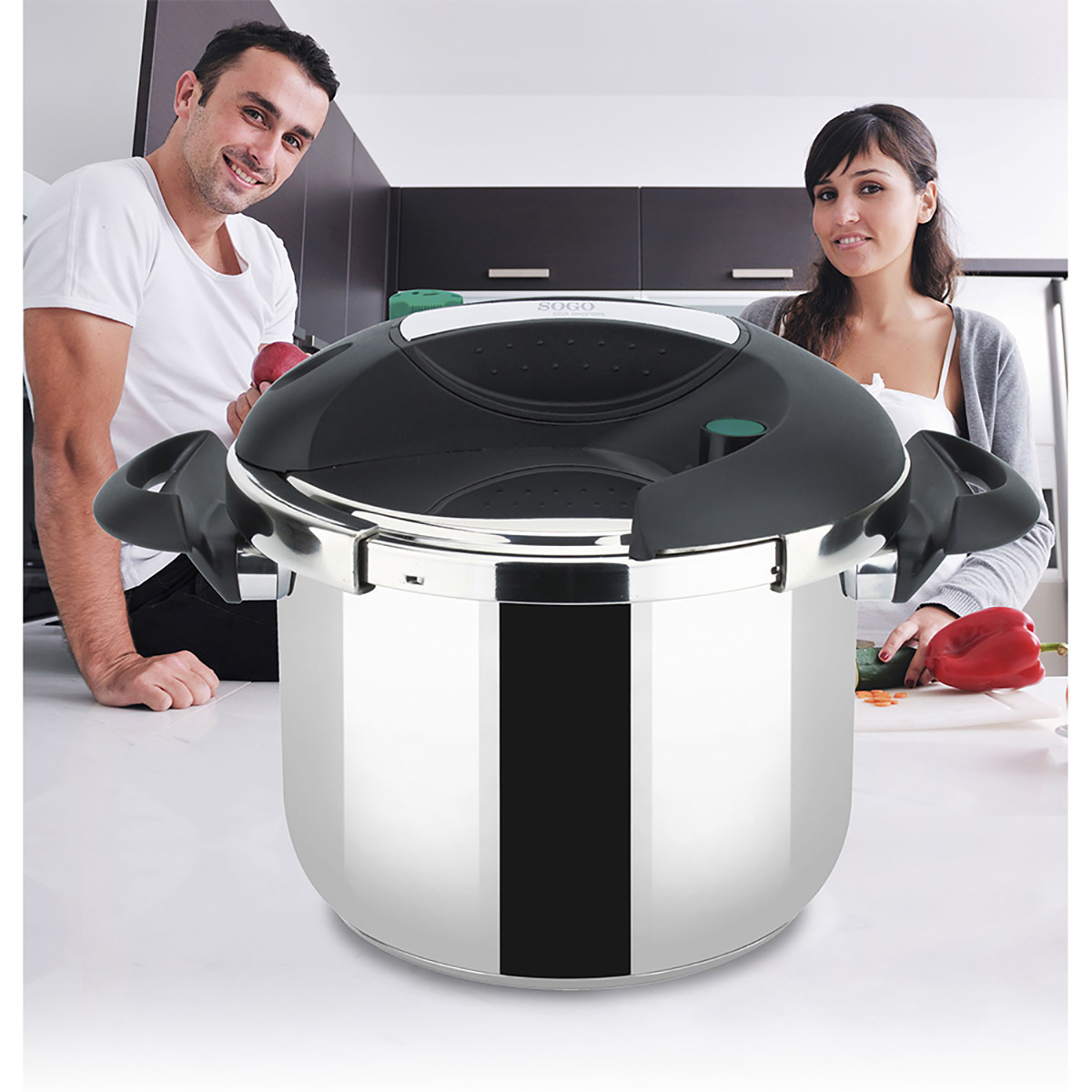 Una pareja en una cocina con una olla a presión. La olla es plateada, con asas negras y cerrada.