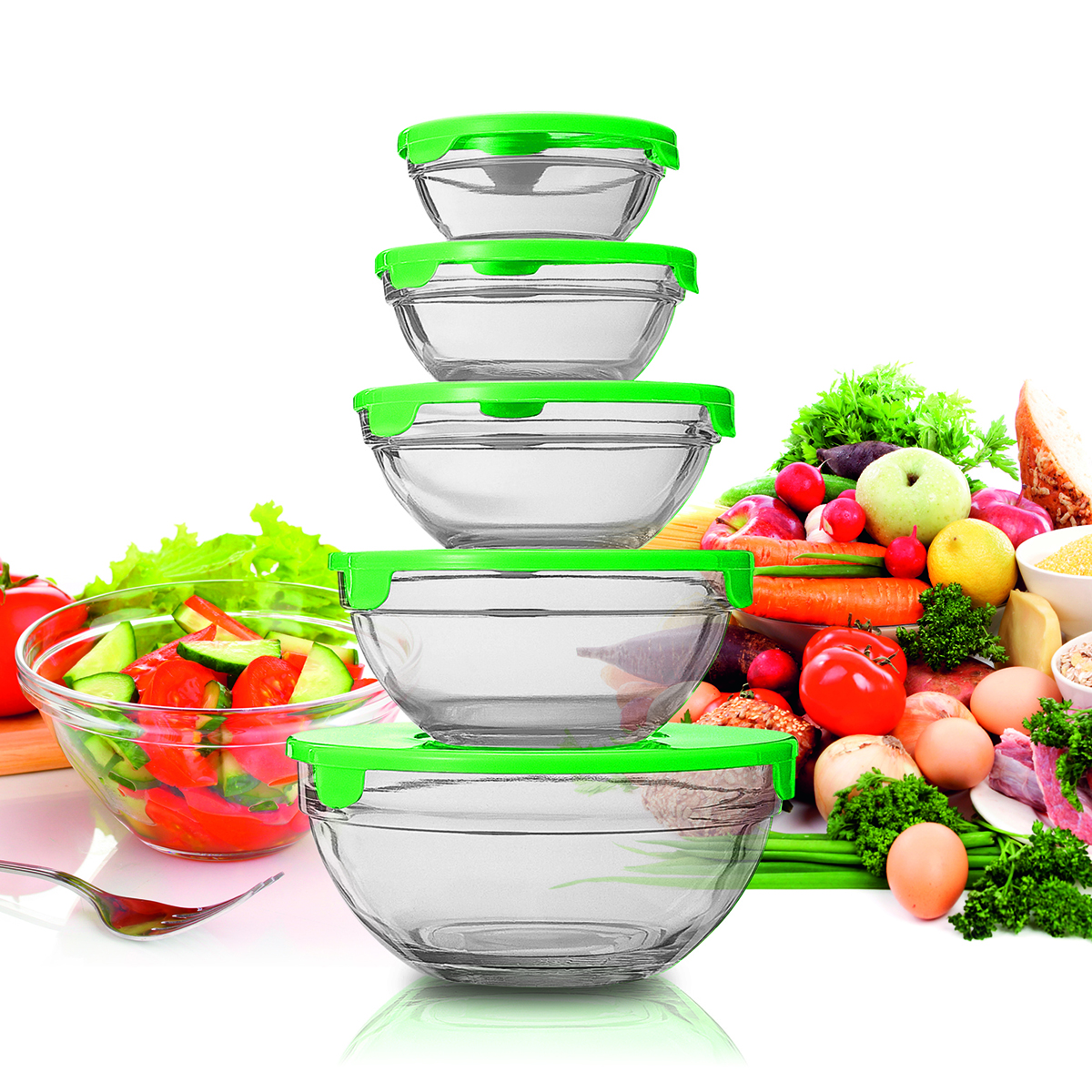 Pila de cuencos de vidrio transparente con tapas verdes. Verduras y alimentos al fondo.