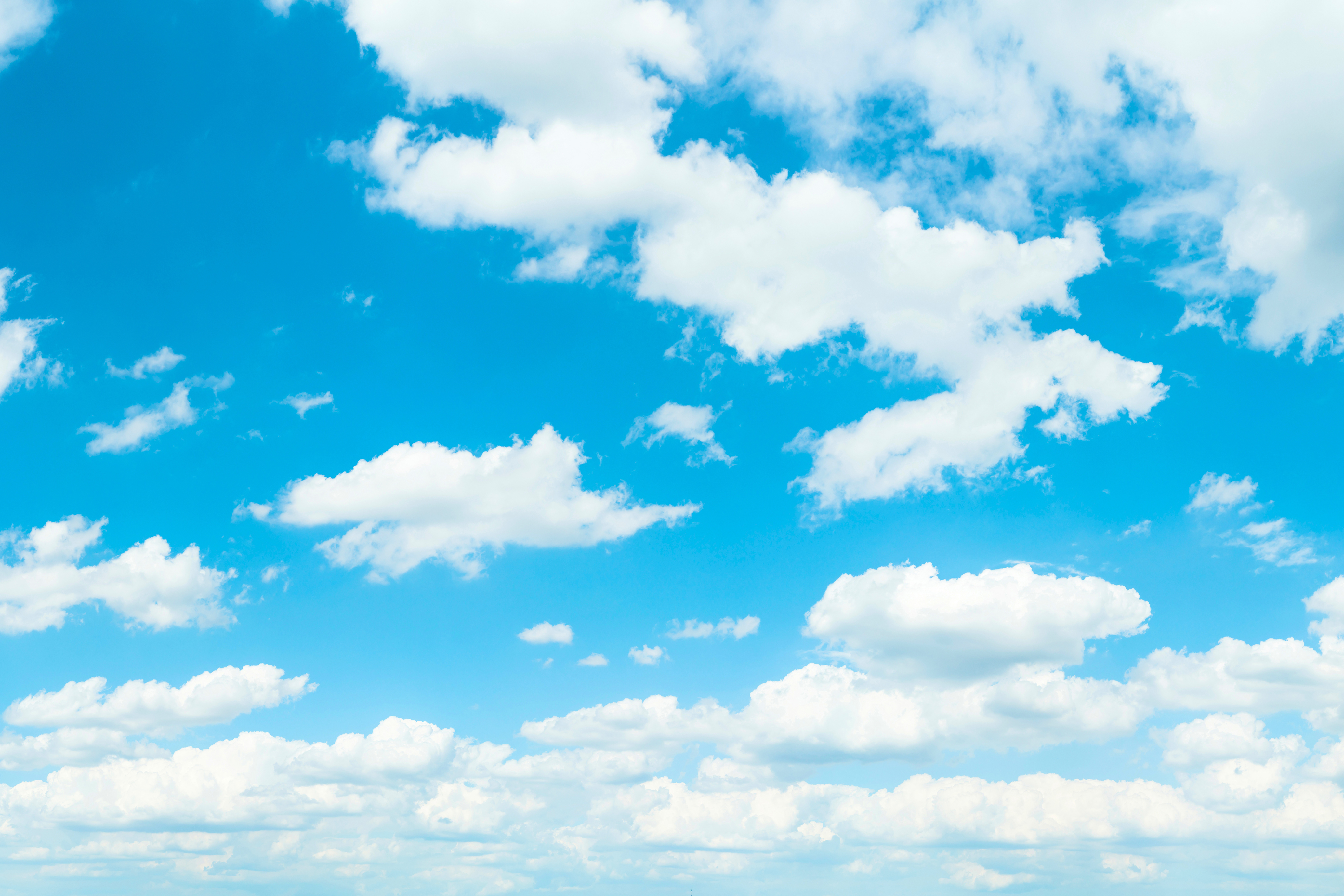 Blauer Himmel mit lockeren weißen Wolken, die über den Rahmen verteilt sind.