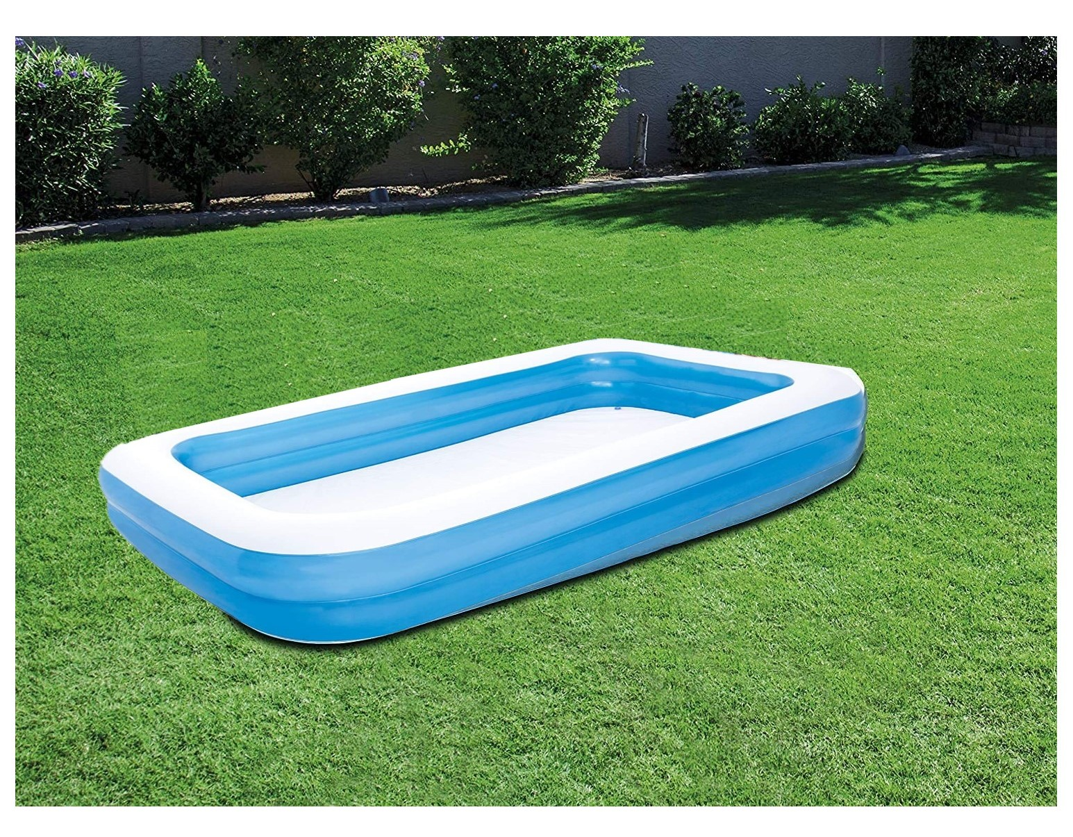 Ein rechteckiger aufblasbarer Swimmingpool, blau und weiß, auf einem grünen Rasen.