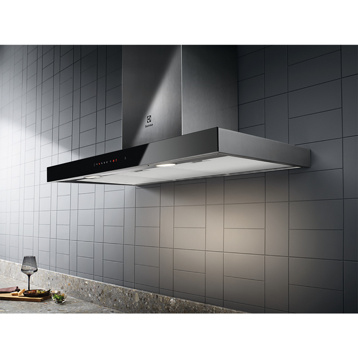 Campana extractora Electrolux de acero inoxidable. Panel negro con luces y controles. Pared de azulejos gris al fondo.