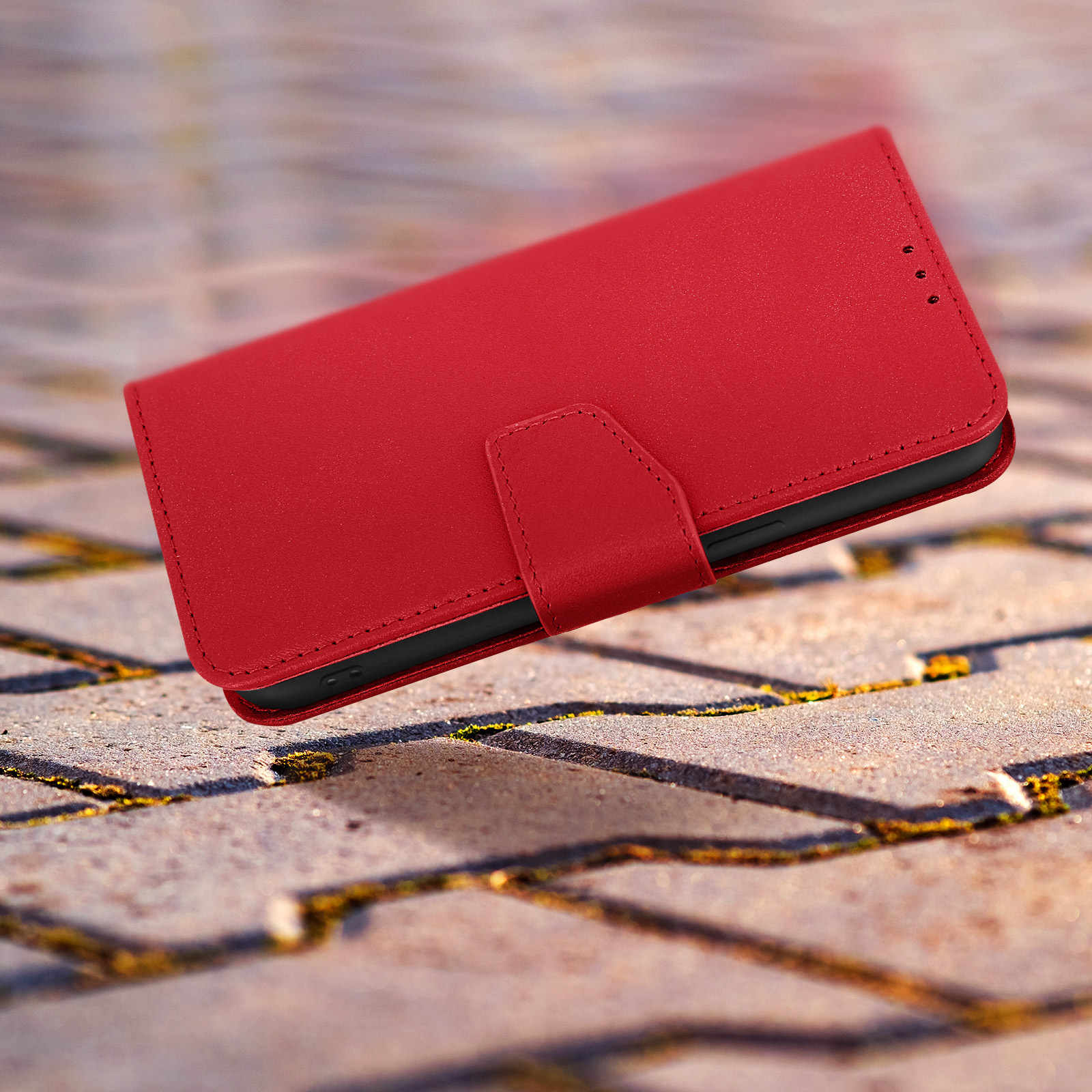 Étui de téléphone rouge ouvert, montrant le téléphone à l'intérieur. Fond flou en pierre.