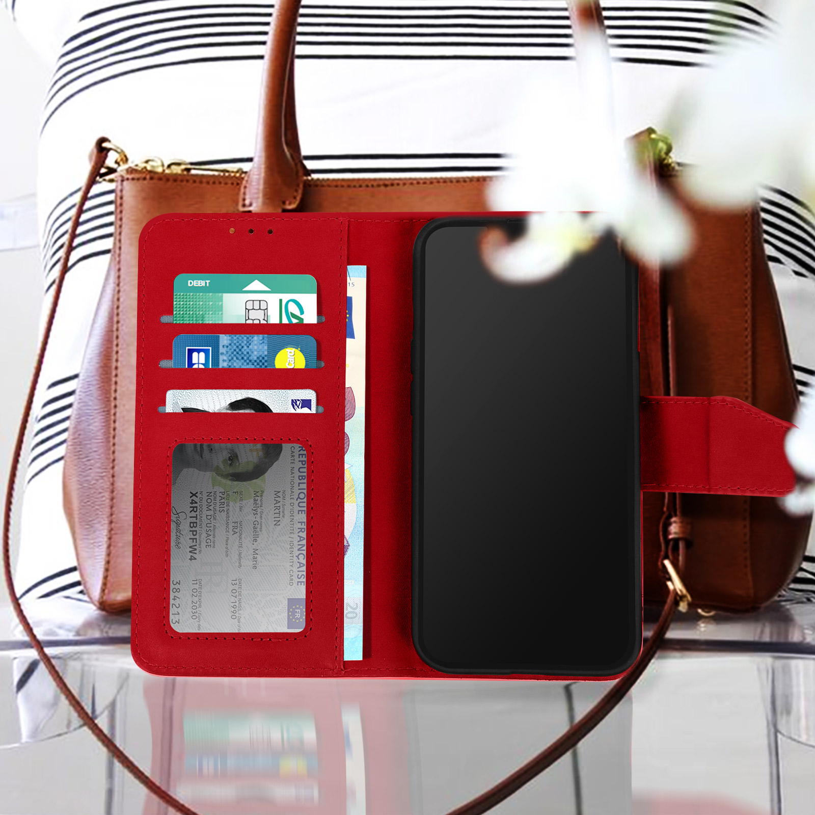 Un étui portefeuille rouge pour téléphone avec un téléphone, des cartes et de l'argent à l'intérieur, tenu par une personne.