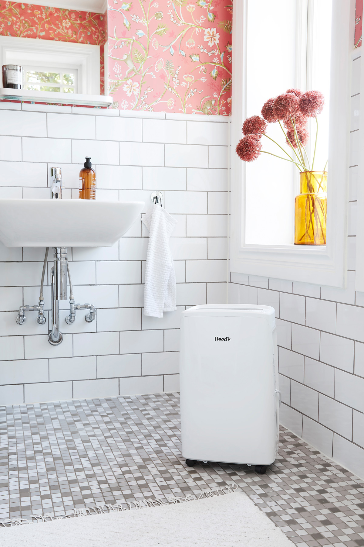 Un bagno con piastrelle bianche, un lavandino e un condizionatore d'aria portatile bianco.
