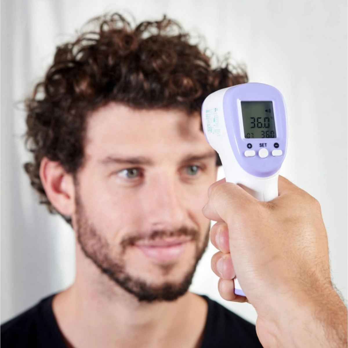 Volto di un uomo scansionato da un termometro digitale, che segna 36.0.