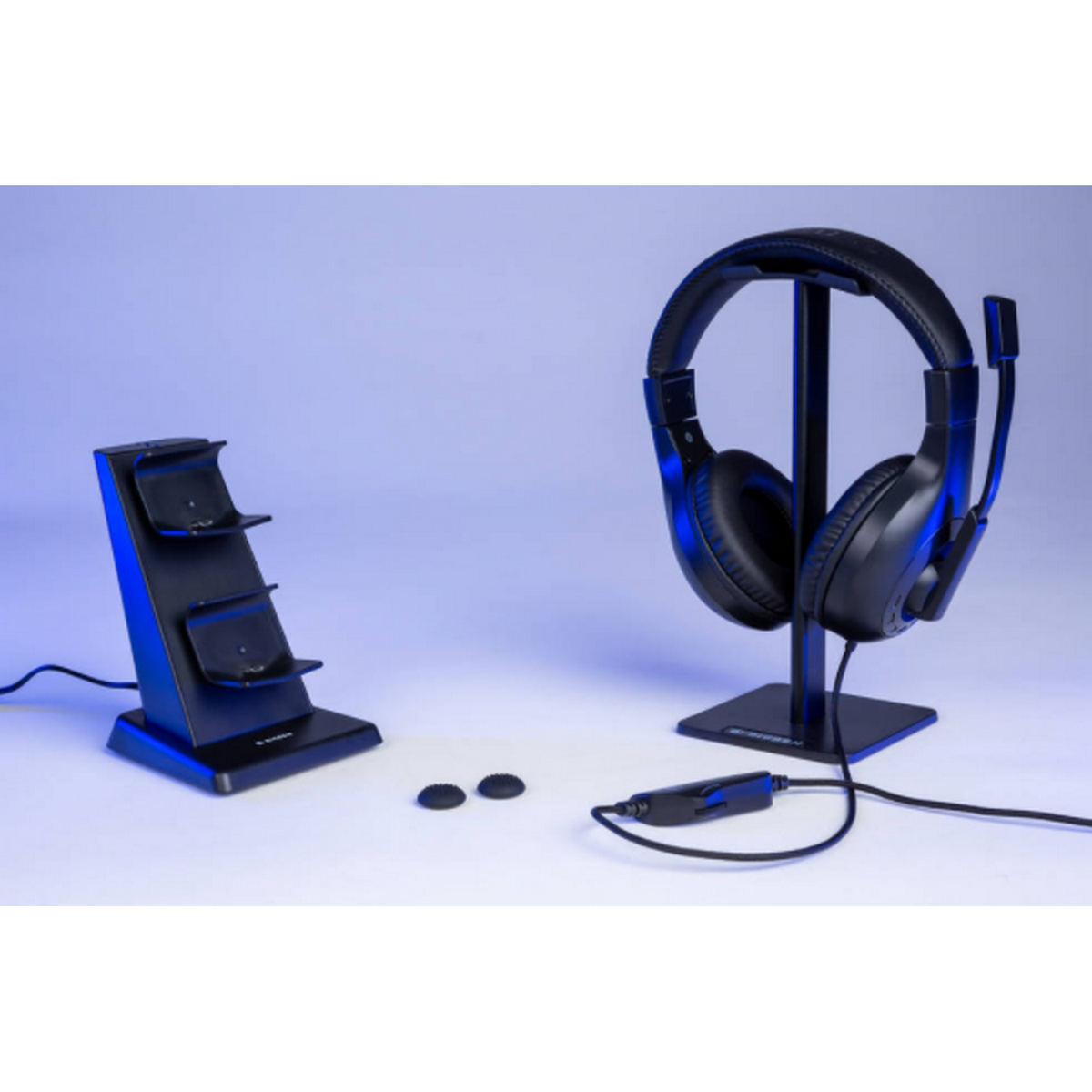 Zestaw słuchawkowy do gier na stojaku, stacja ładująca i dwie dodatkowe wkładki douszne na niebieskim tle.