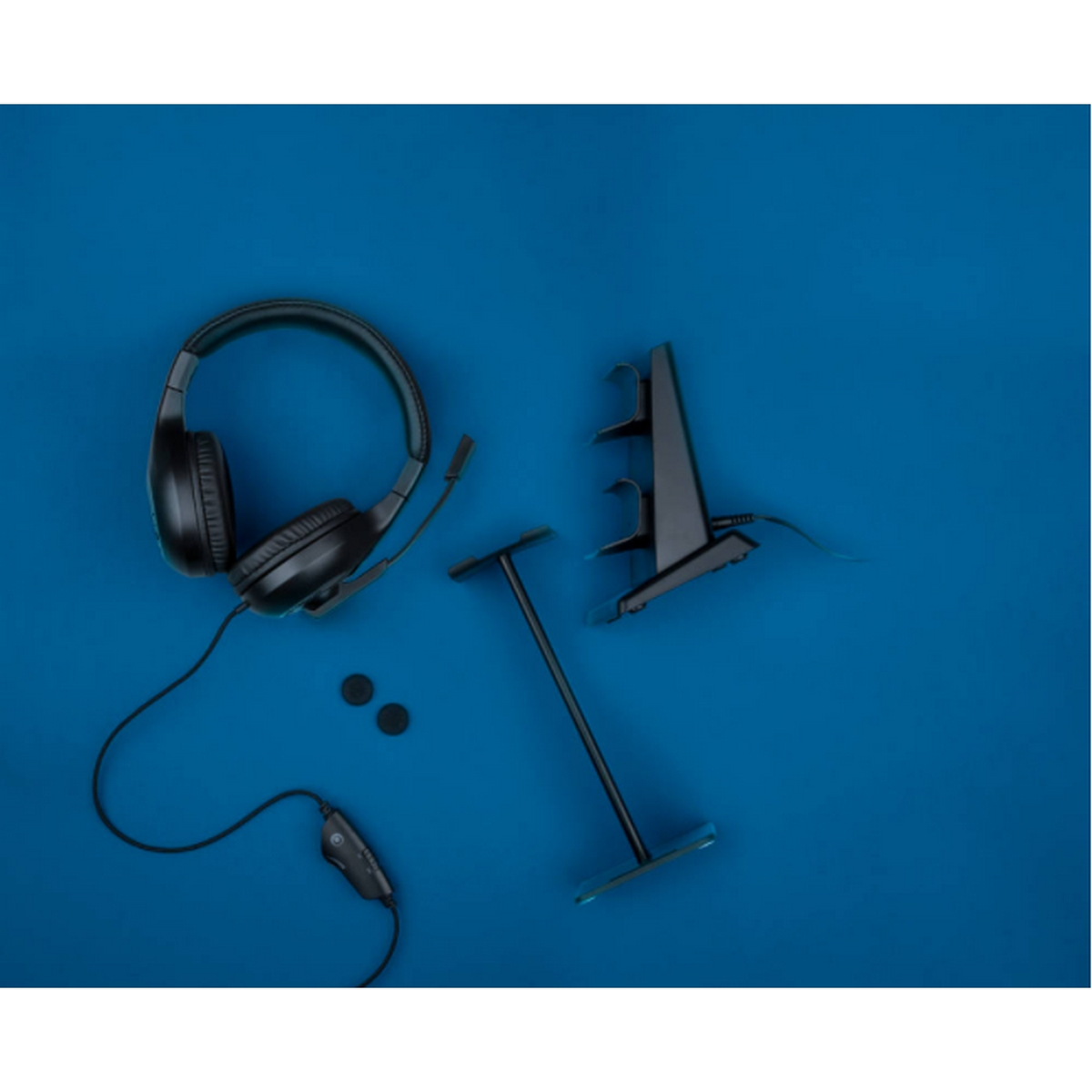 Czarne słuchawki, mikrofon na wysięgniku i akcesoria na niebieskim tle, widok z góry.