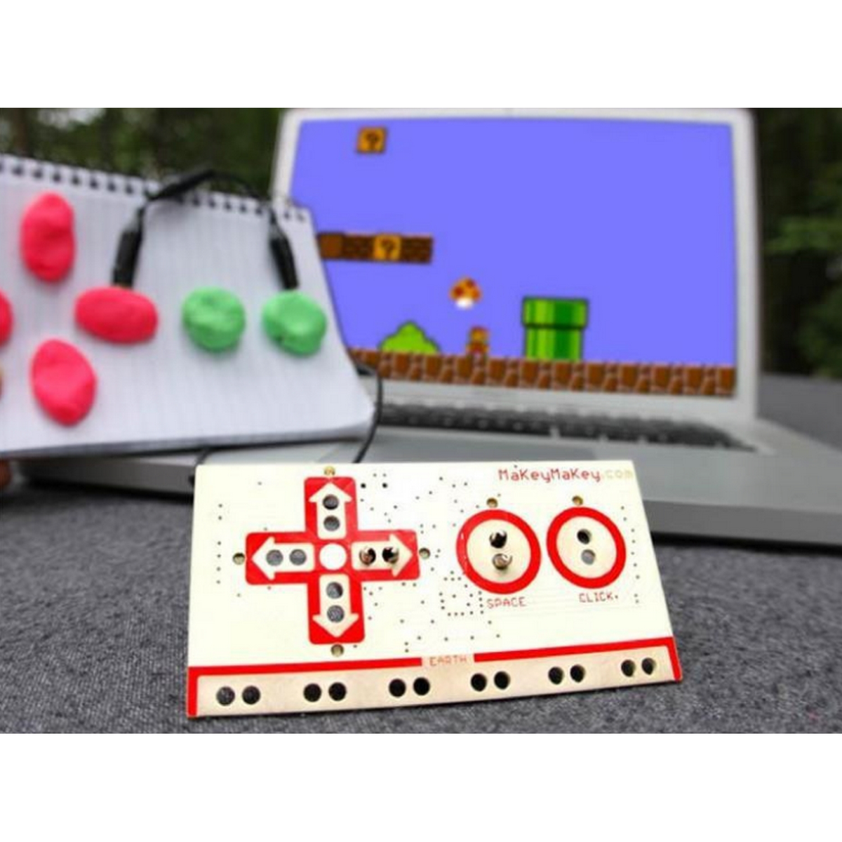 Un controlador blanco con botones rojos y un portátil que muestra un juego de Super Mario Bros.