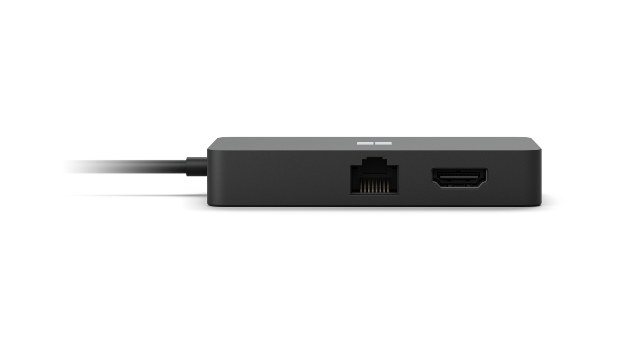 Un hub Microsoft nero con porte Ethernet e HDMI e un cavo nero che si estende verso sinistra su una superficie bianca.