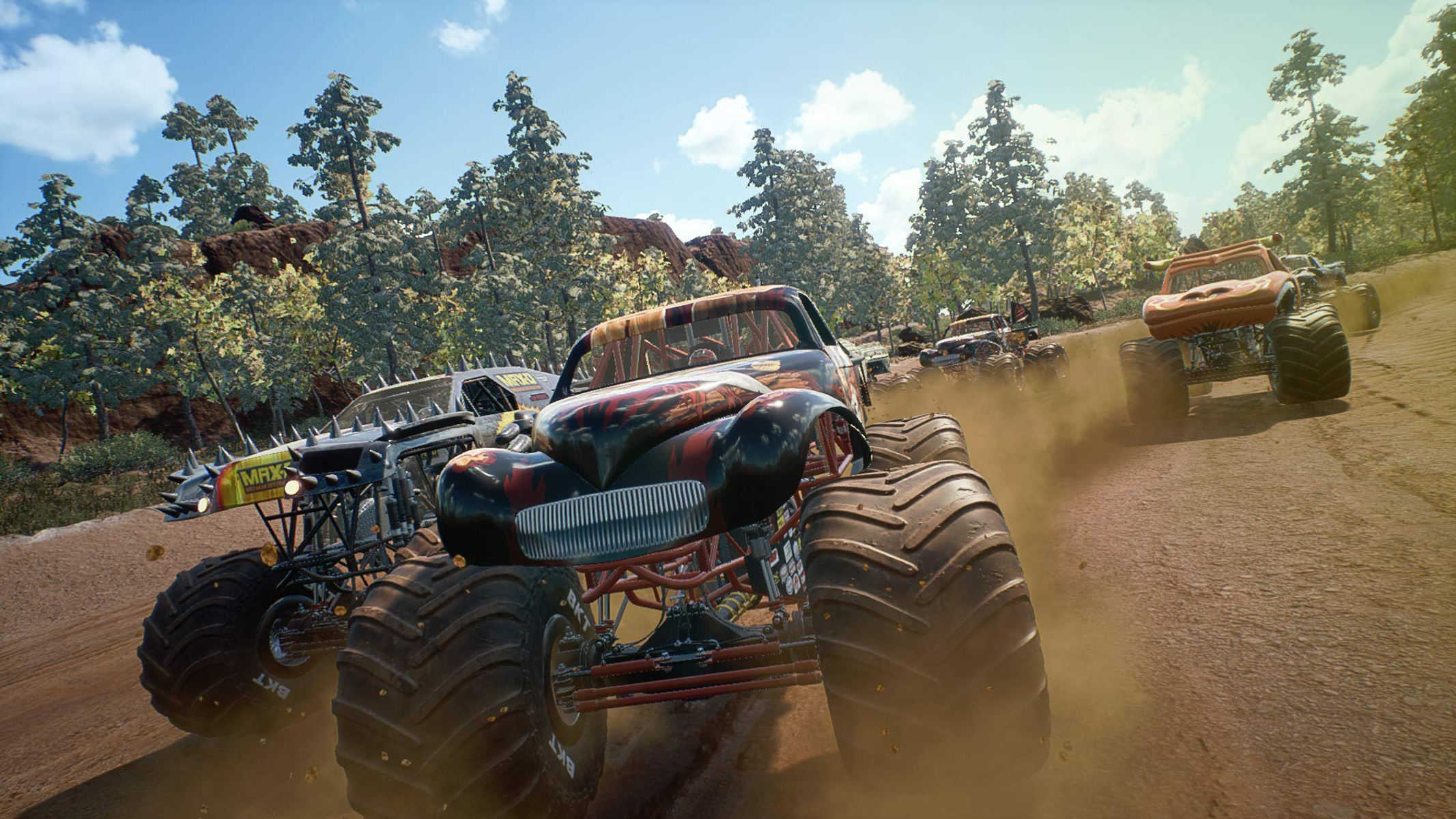 Monster truck che corrono su una pista sterrata. Diversi camion sono visibili, sollevando polvere. Alberi e cielo sullo sfondo.