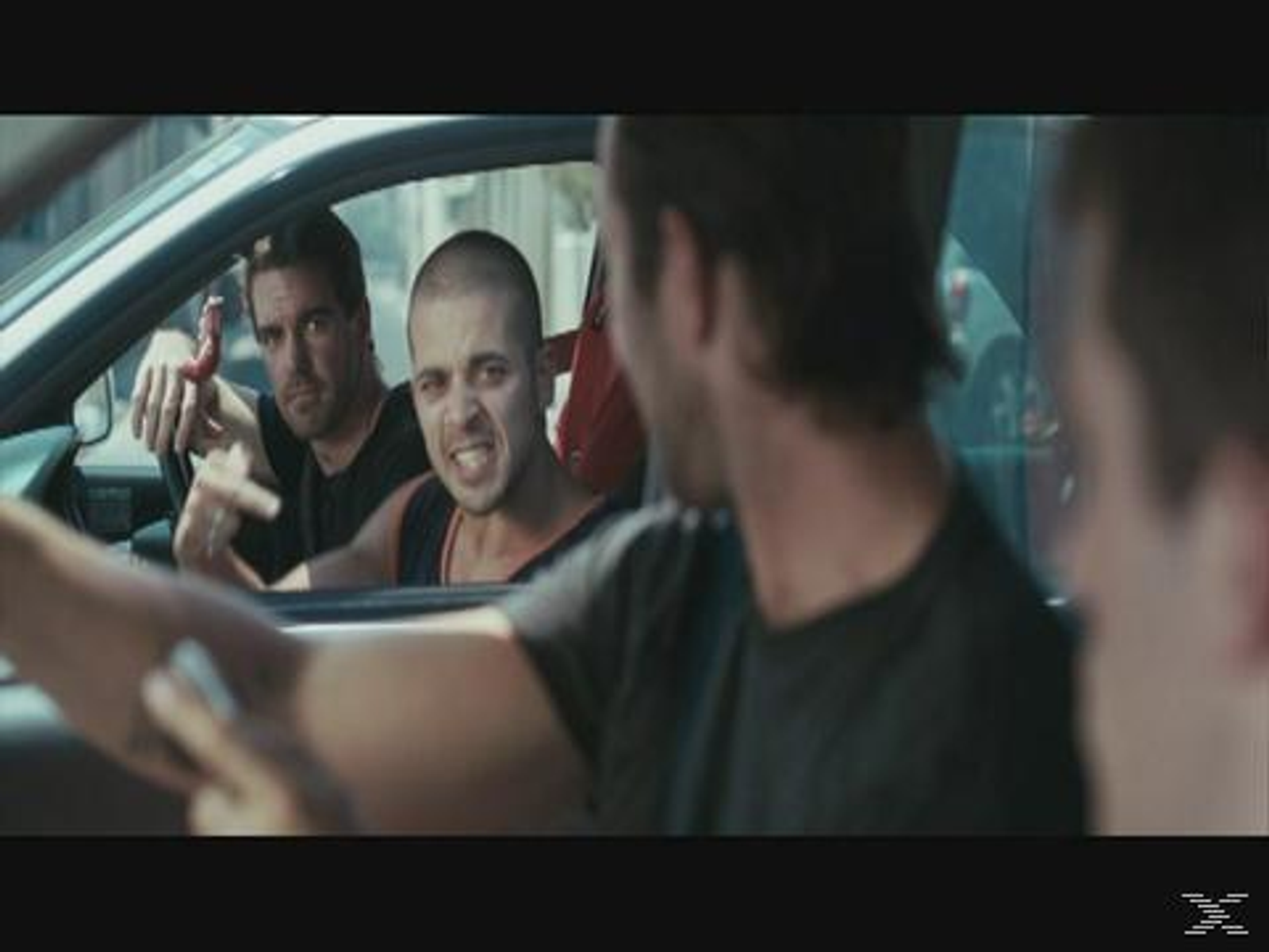Tres hombres en un coche, uno gritando. Uno está señalando.