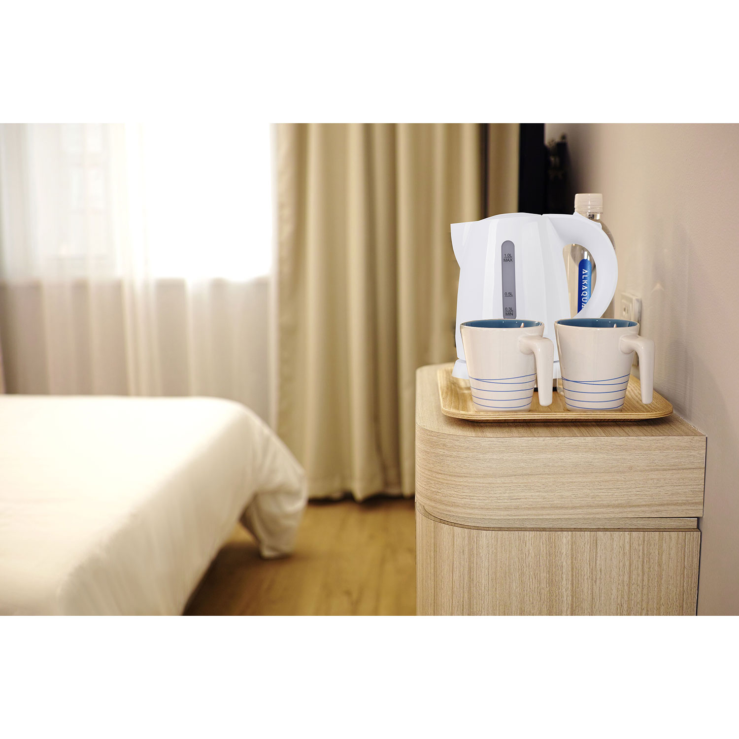 Pokój hotelowy z łóżkiem, stołem, czajnikiem i dwoma kubkami. Rozmyte tło.