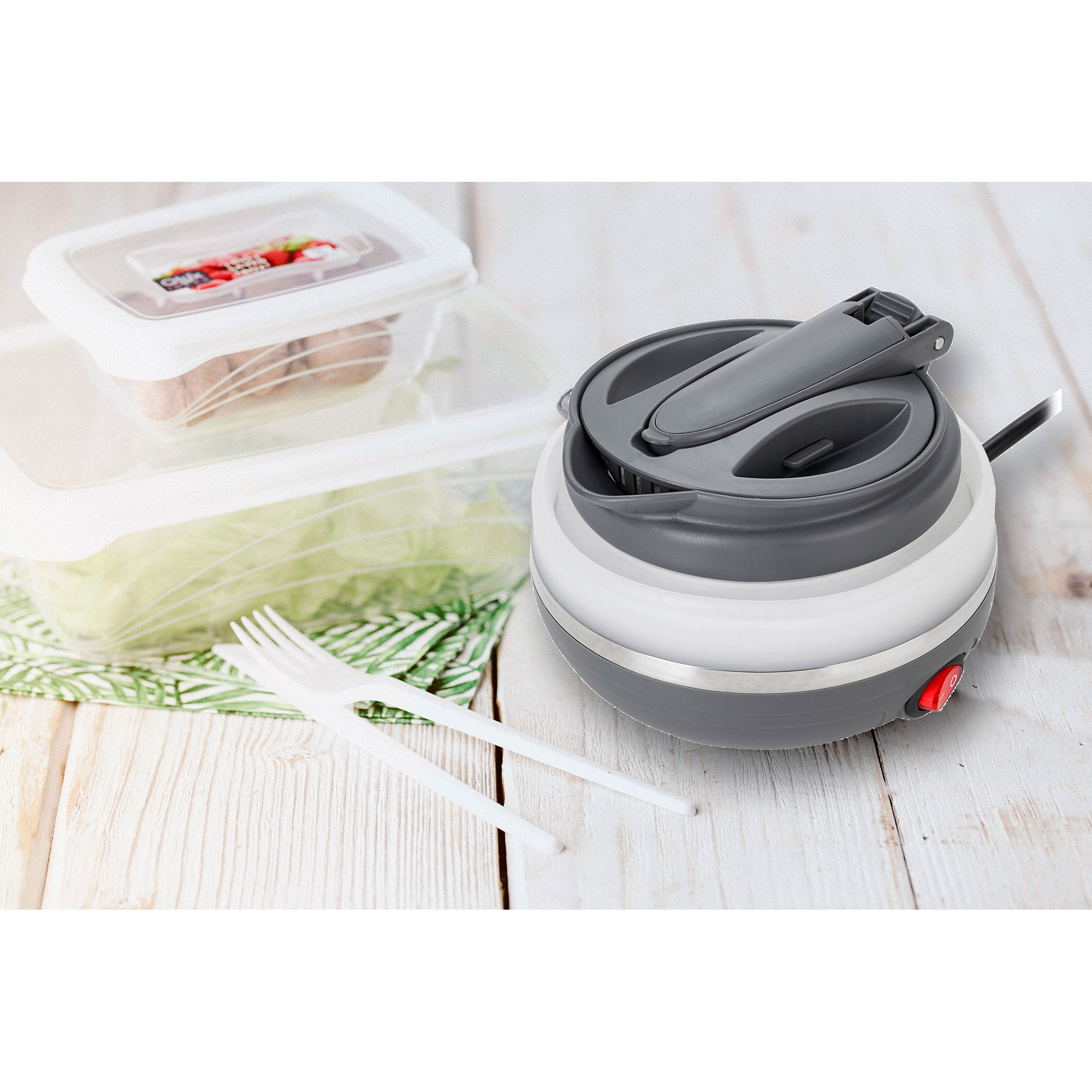 Składany szaro-biały czajnik elektryczny. Dwa białe widelce i pojemniki na jedzenie na drewnie.