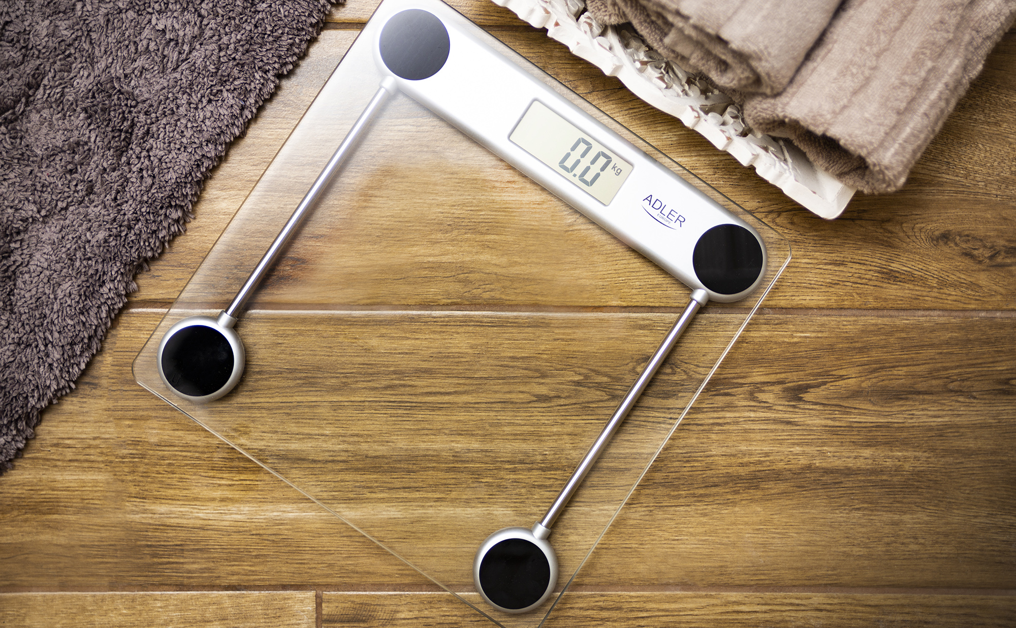 Glaswaage mit digitaler Anzeige 0,0 kg. Ein Handtuch und eine Holzoberfläche sind ebenfalls im Bild.