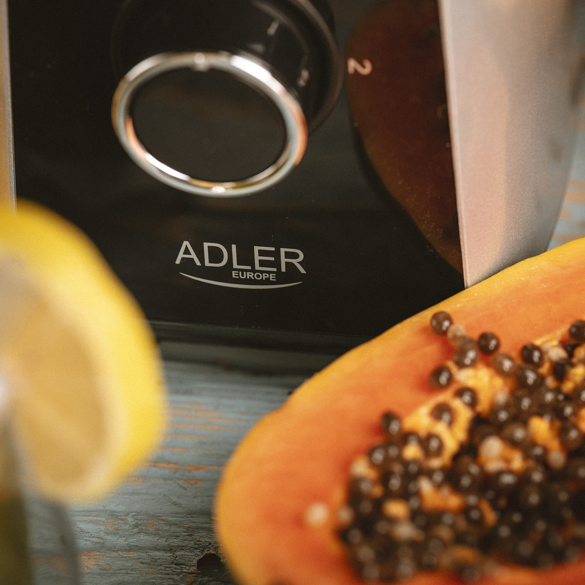 Zbliżenie czarnego robota kuchennego ze plasterkiem cytryny i papają.