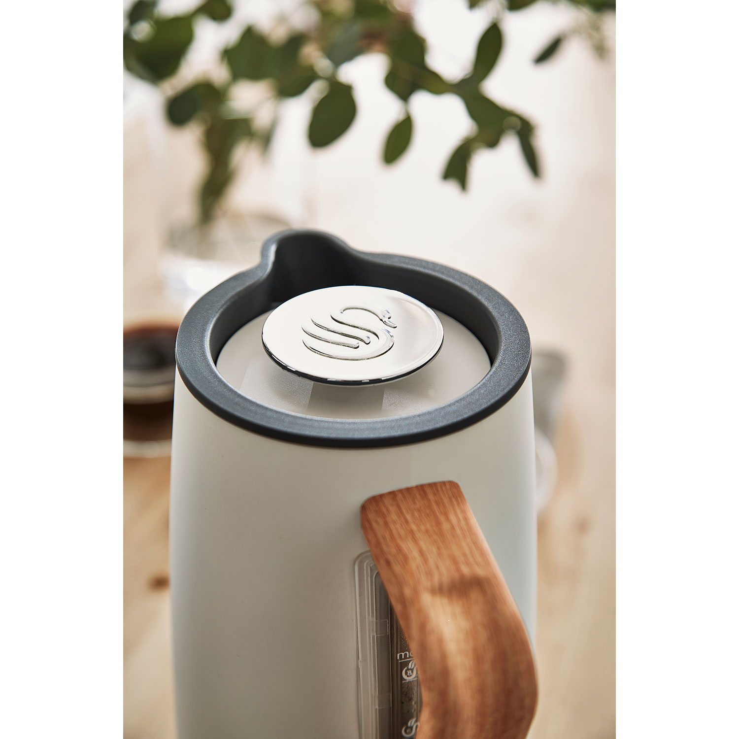 Zbliżenie białego i szarego czajnika z drewnianym uchwytem i srebrną pokrywką.