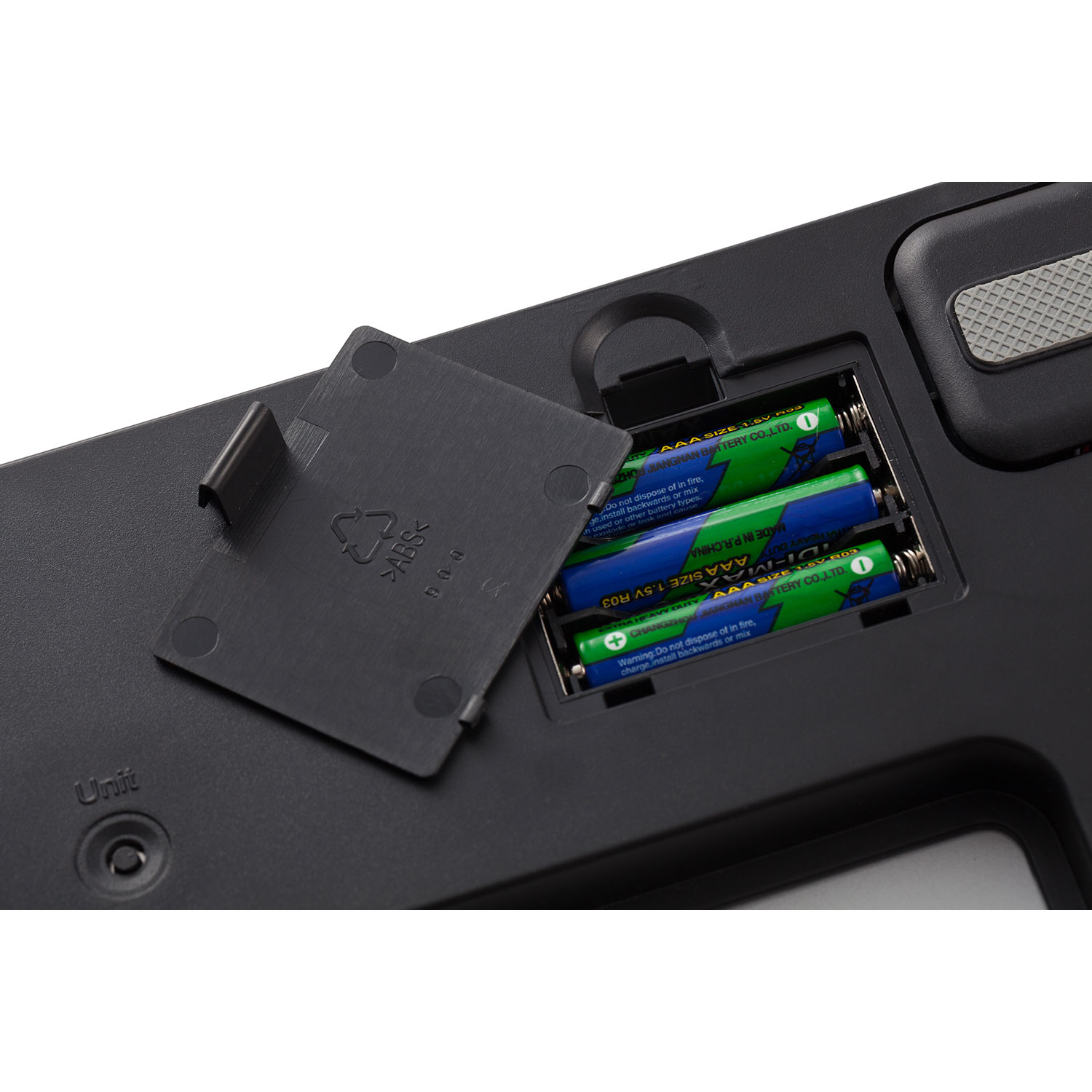 Zwart apparaat met batterijen. Klep open, met drie groene AAA-batterijen.
