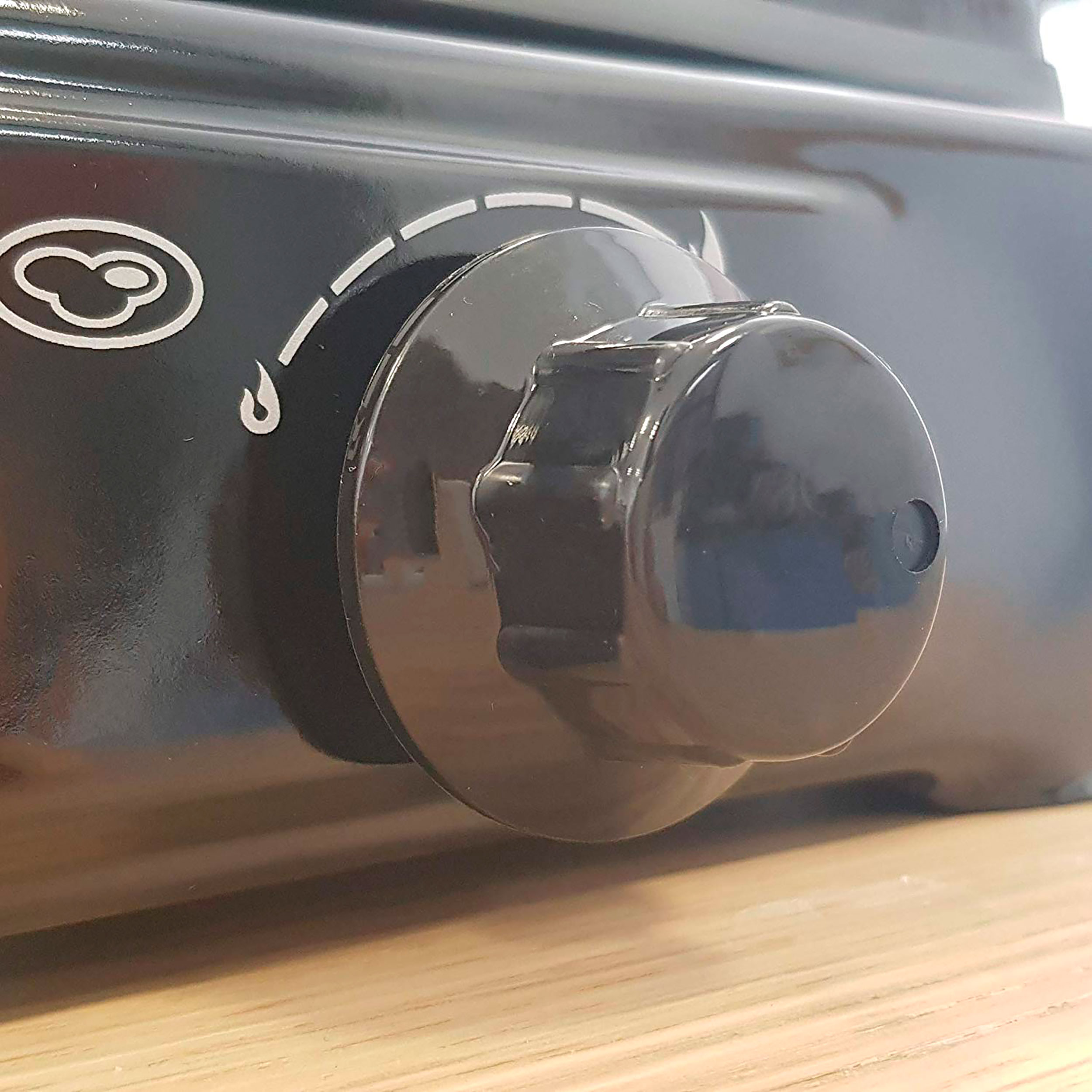 Primo piano di una manopola nera del fornello con superficie strutturata. Ha un segno bianco.