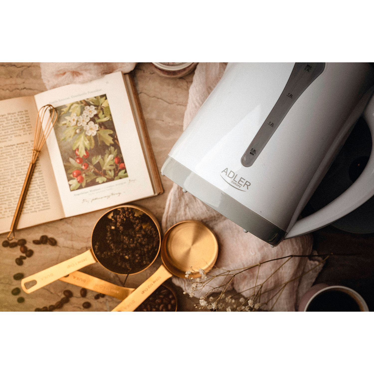 Przygotowanie kawy: czajnik, otwarta książka, łyżki miarowe, ziarna kawy i filiżanka kawy.