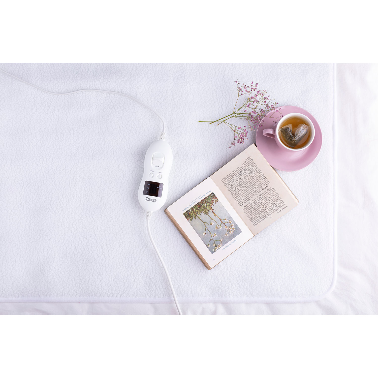 Weißer Heizdeckenregler mit Buch, Tee und Blume auf einem Bett.
