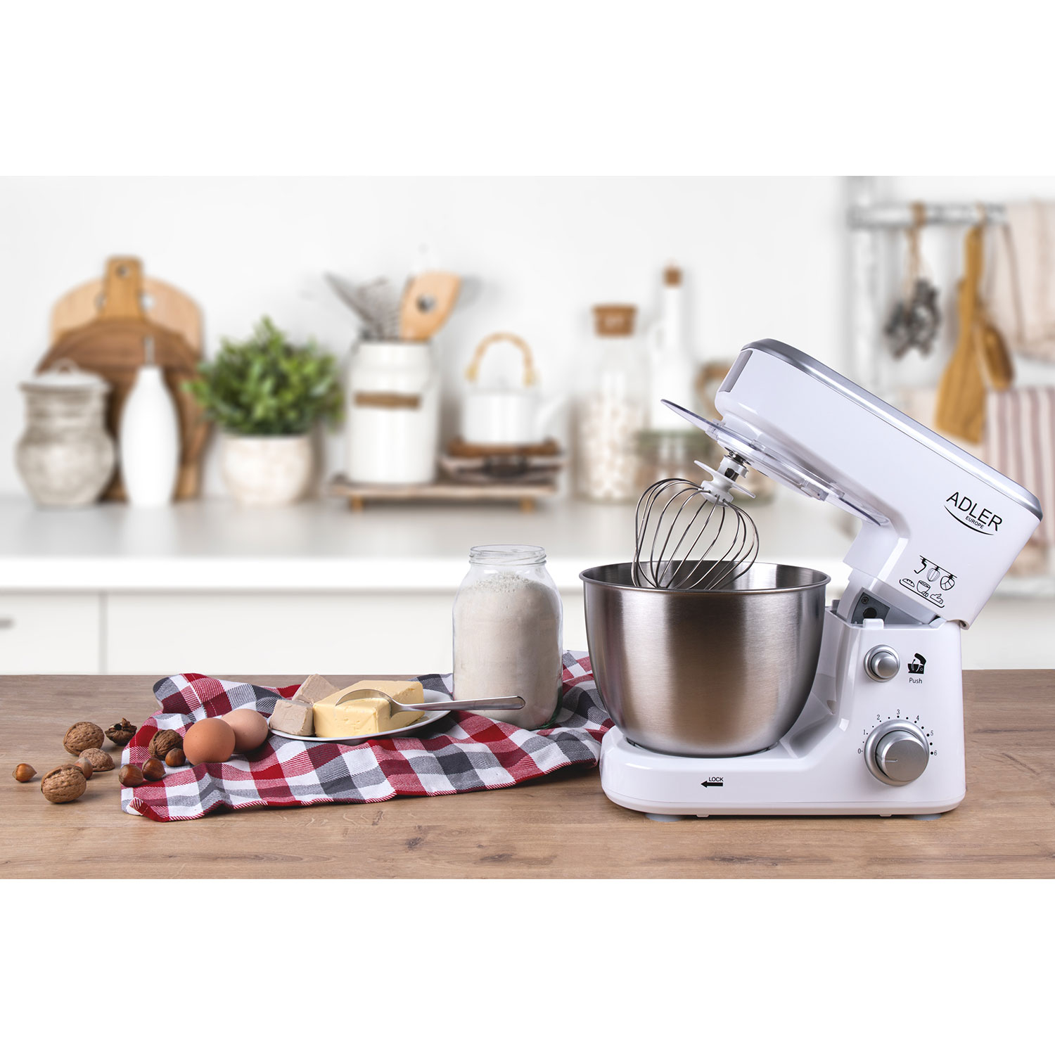 Ein weißer Küchenmixer mit Zutaten auf einem Holztisch. Der Mixer ist aufgebaut und einsatzbereit. Fokus auf dem Mixer.