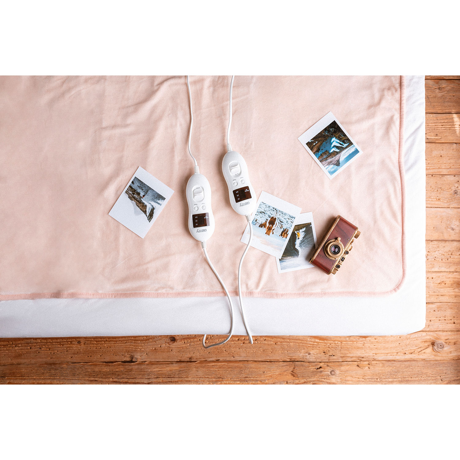 Coperta elettrica rosa con comandi e foto. Pavimento in legno.