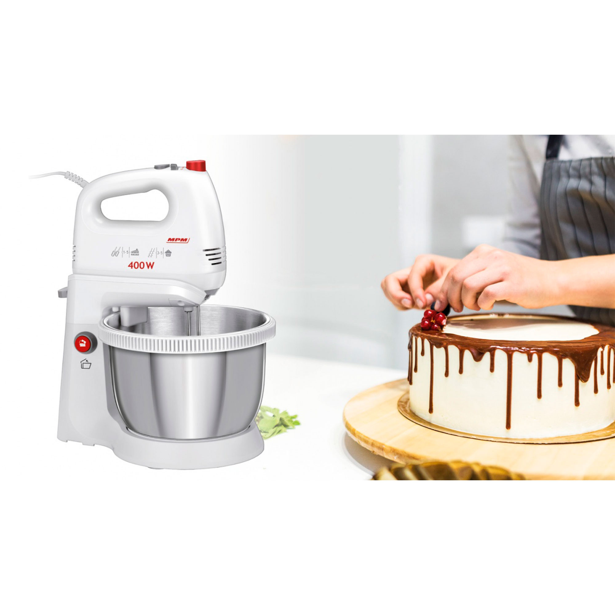 Biały mikser ręczny ze stalową misą i osoba dekorująca ciasto.