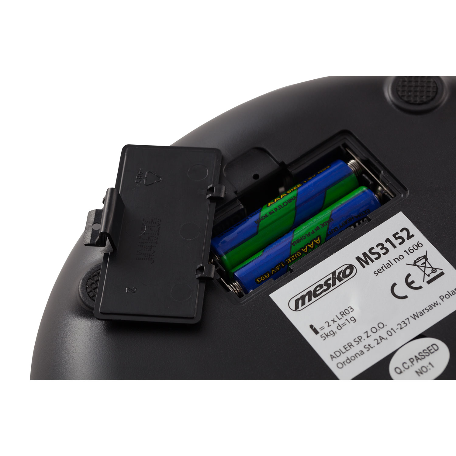 Zbliżenie czarnej wagi z bateriami w otwartej komorze. Widoczne logo Mesko.