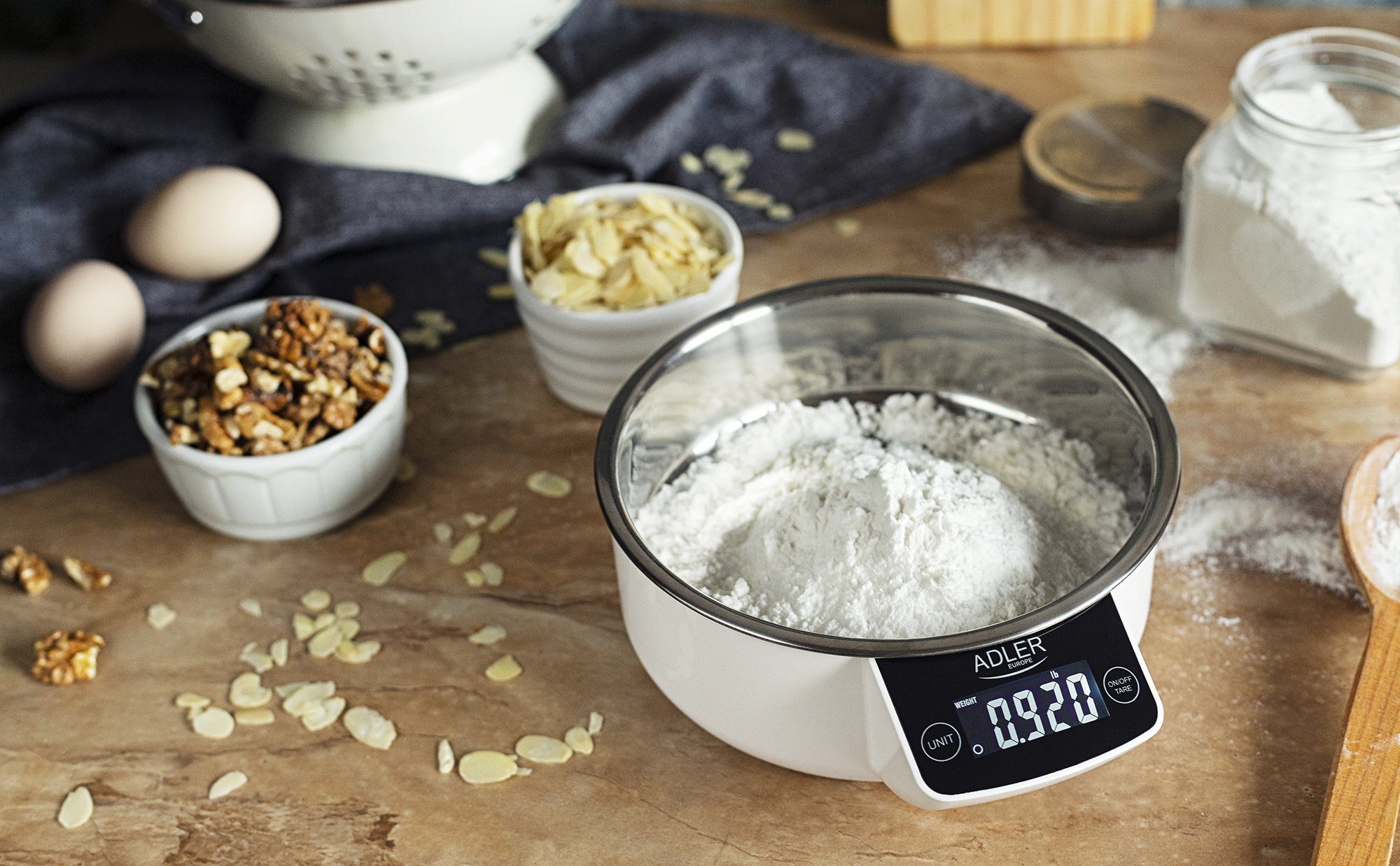 Waga z mąką, orzechami i jajkami na drewnianym stole.