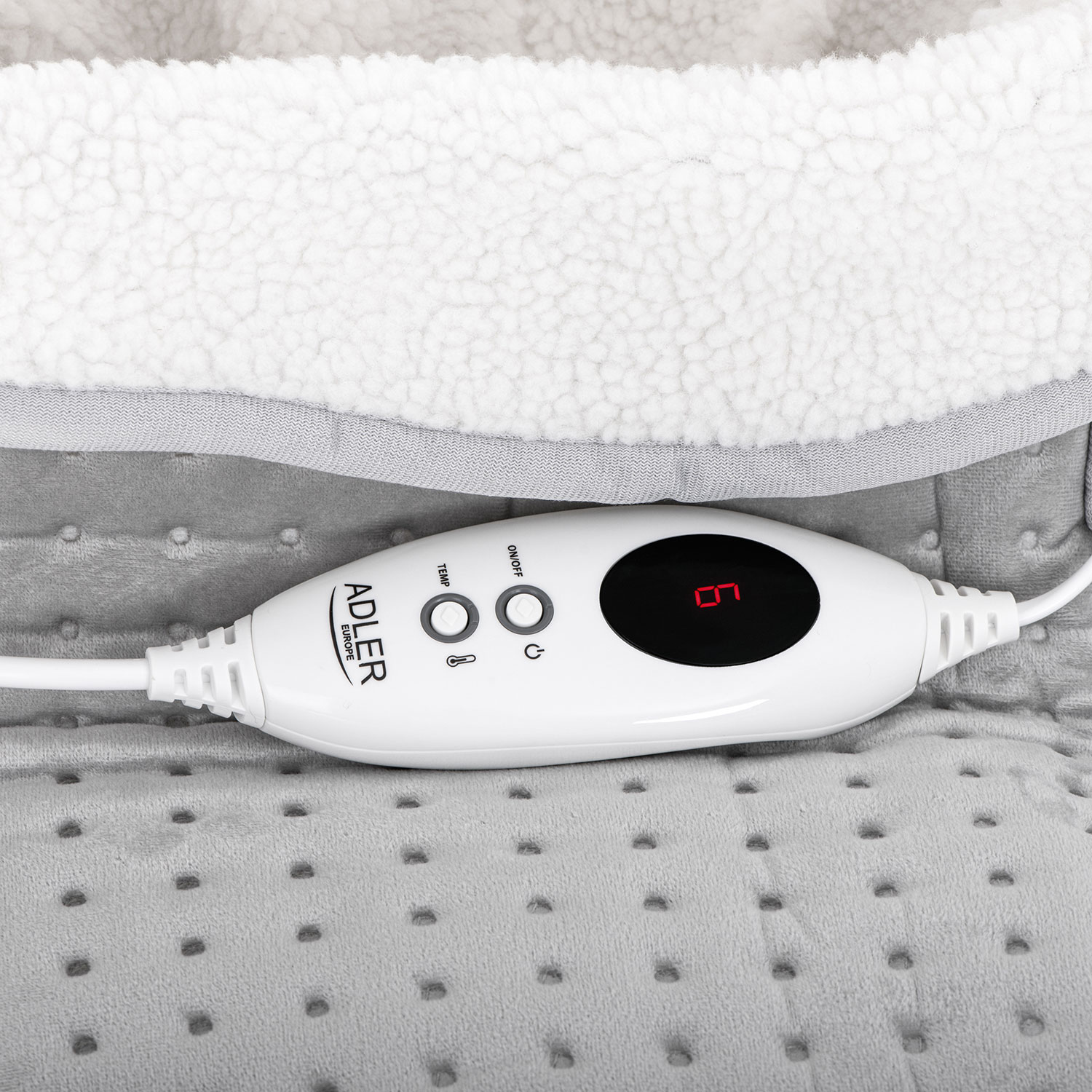 Weiße Heizdeckensteuerung mit Digitalanzeige, graue Decke darunter. Weißes Kabel erstreckt sich von der Steuerung.