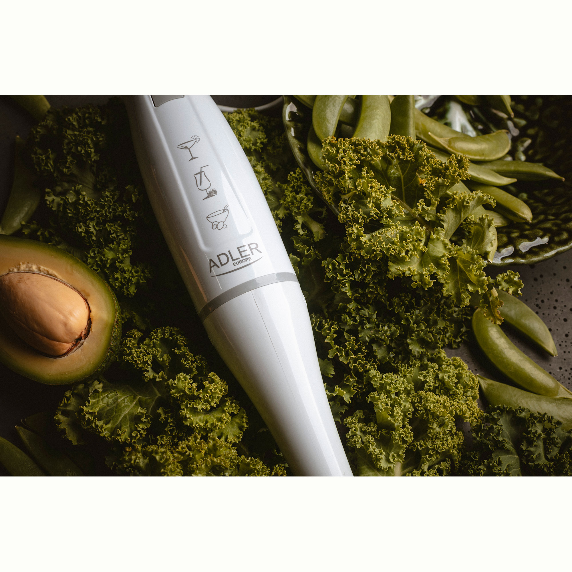 Witte staafmixer met avocado en groene groenten.