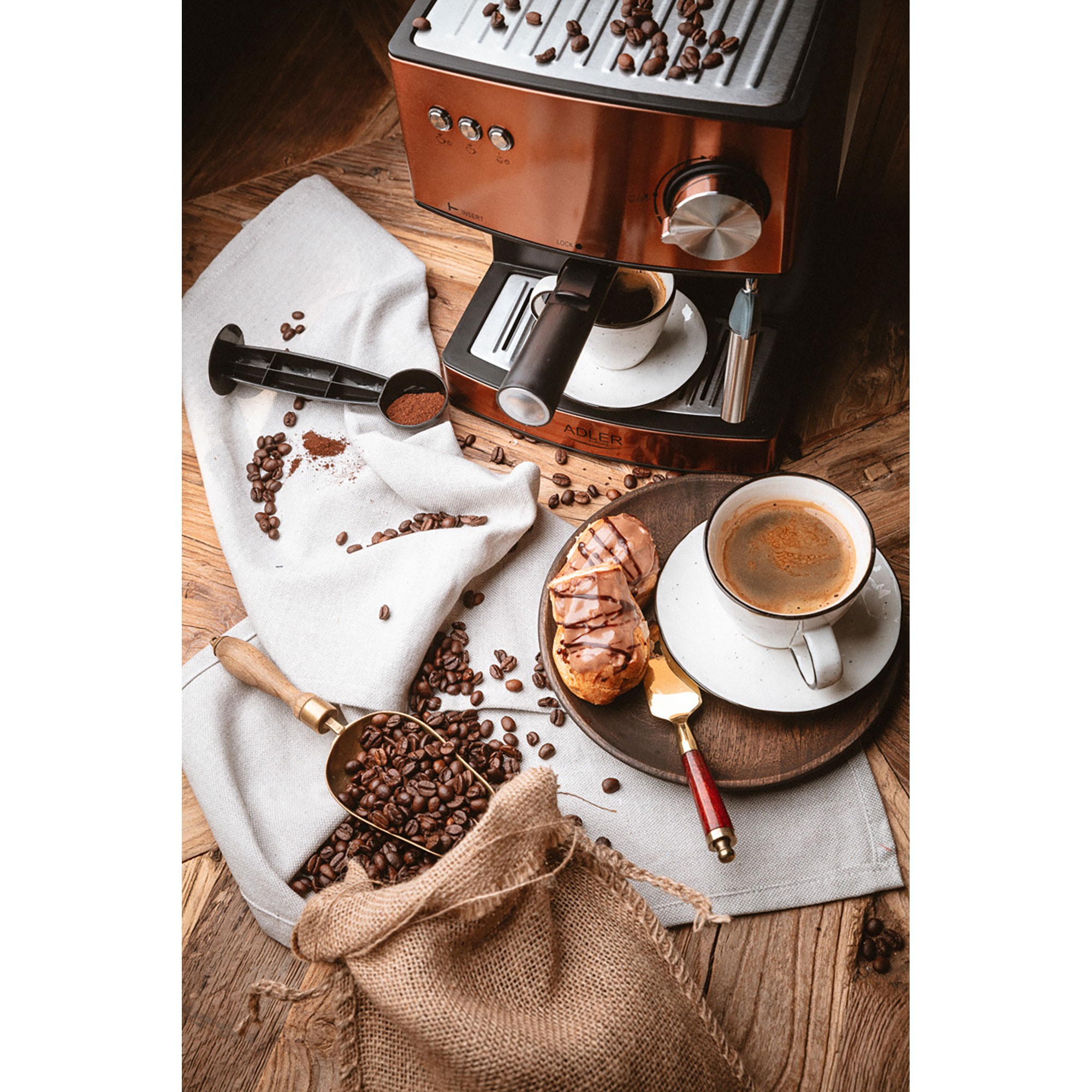 Macchina da caffè, caffè, chicchi e accessori su un tavolo di legno.