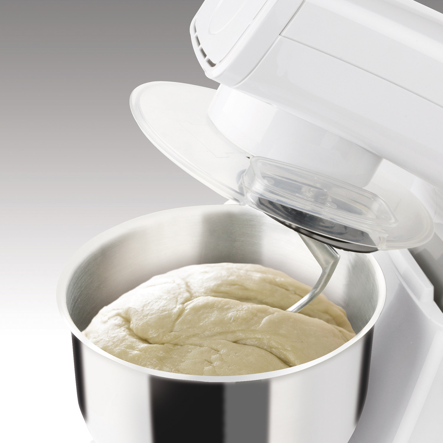 Batidora de cocina blanca con masa en el cuenco de acero inoxidable. Tapa transparente.