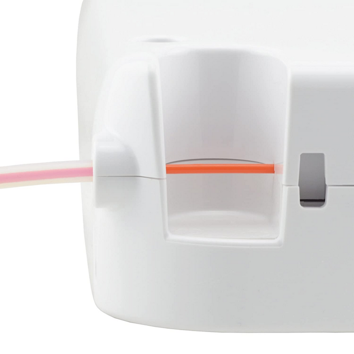 Un objeto blanco con una ranura que contiene un cable naranja, toma de primer plano.