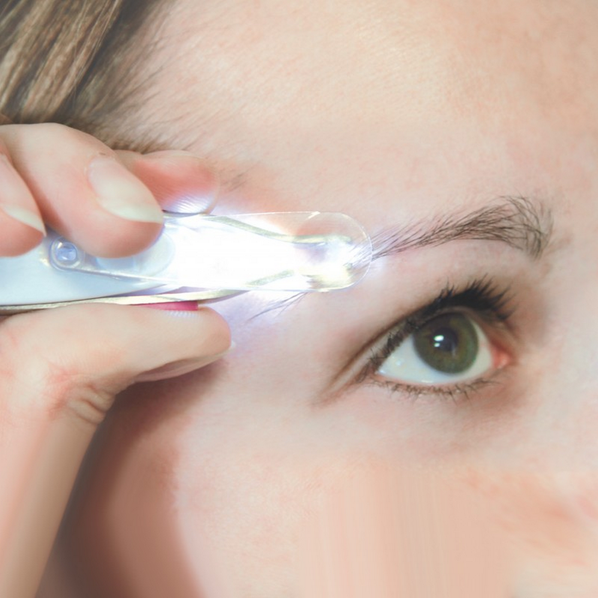 Ojo de mujer examinado con una herramienta de aumento iluminada. Primer plano.