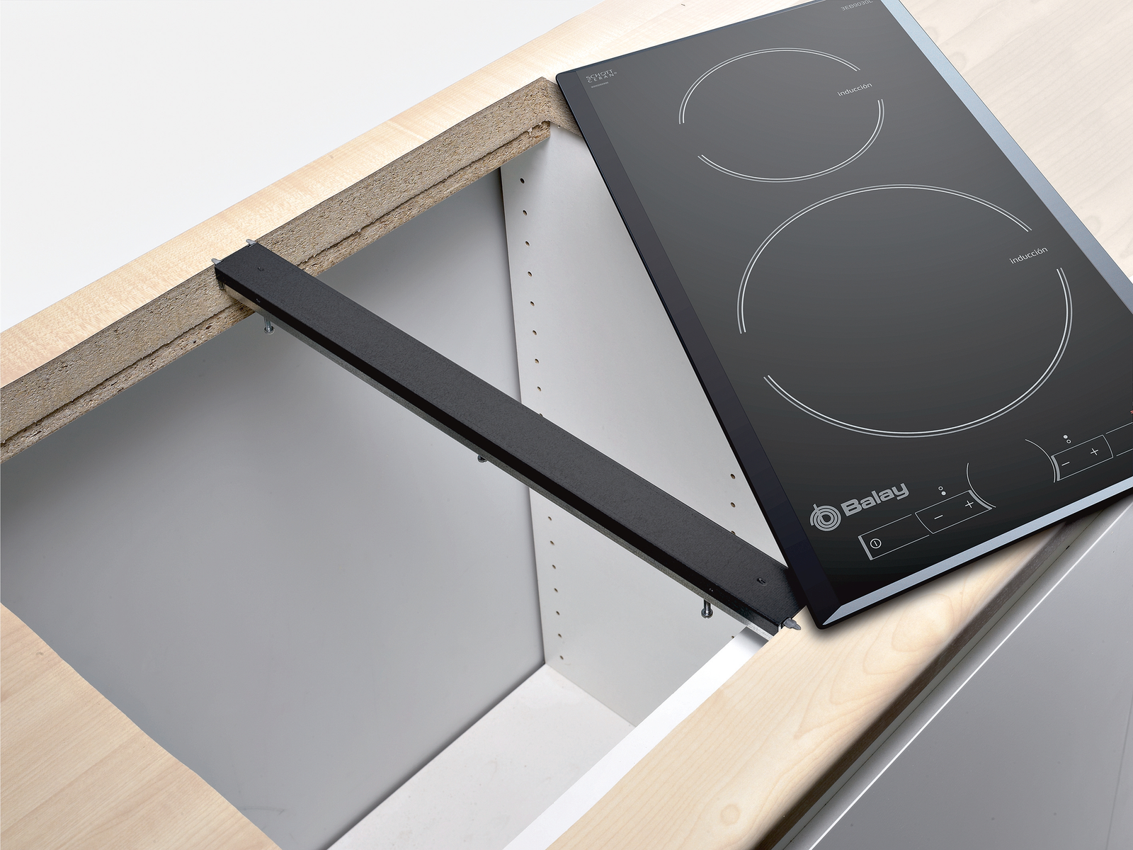 Placa de inducción negra instalada en encimera de madera, con hueco para el electrodoméstico y barra de soporte.