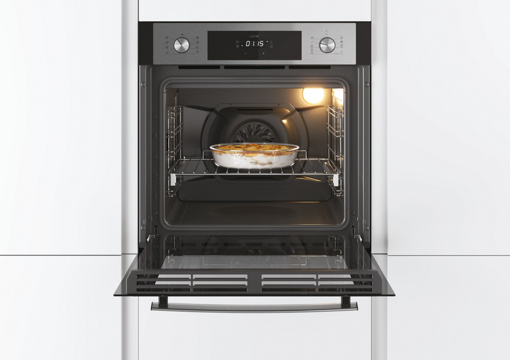 Un forno aperto con un piatto di cibo all'interno, illuminato dall'interno. Mobili bianchi sullo sfondo.