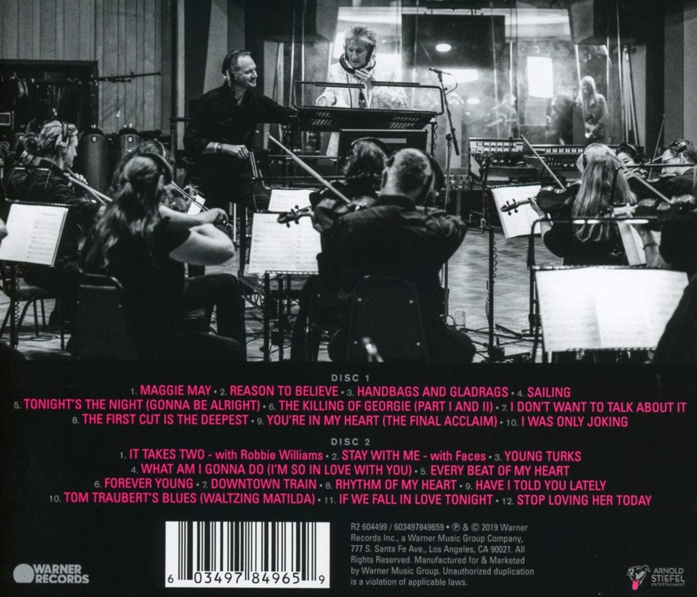 Un'orchestra si esibisce in studio, con musicisti e direttore visibili.
