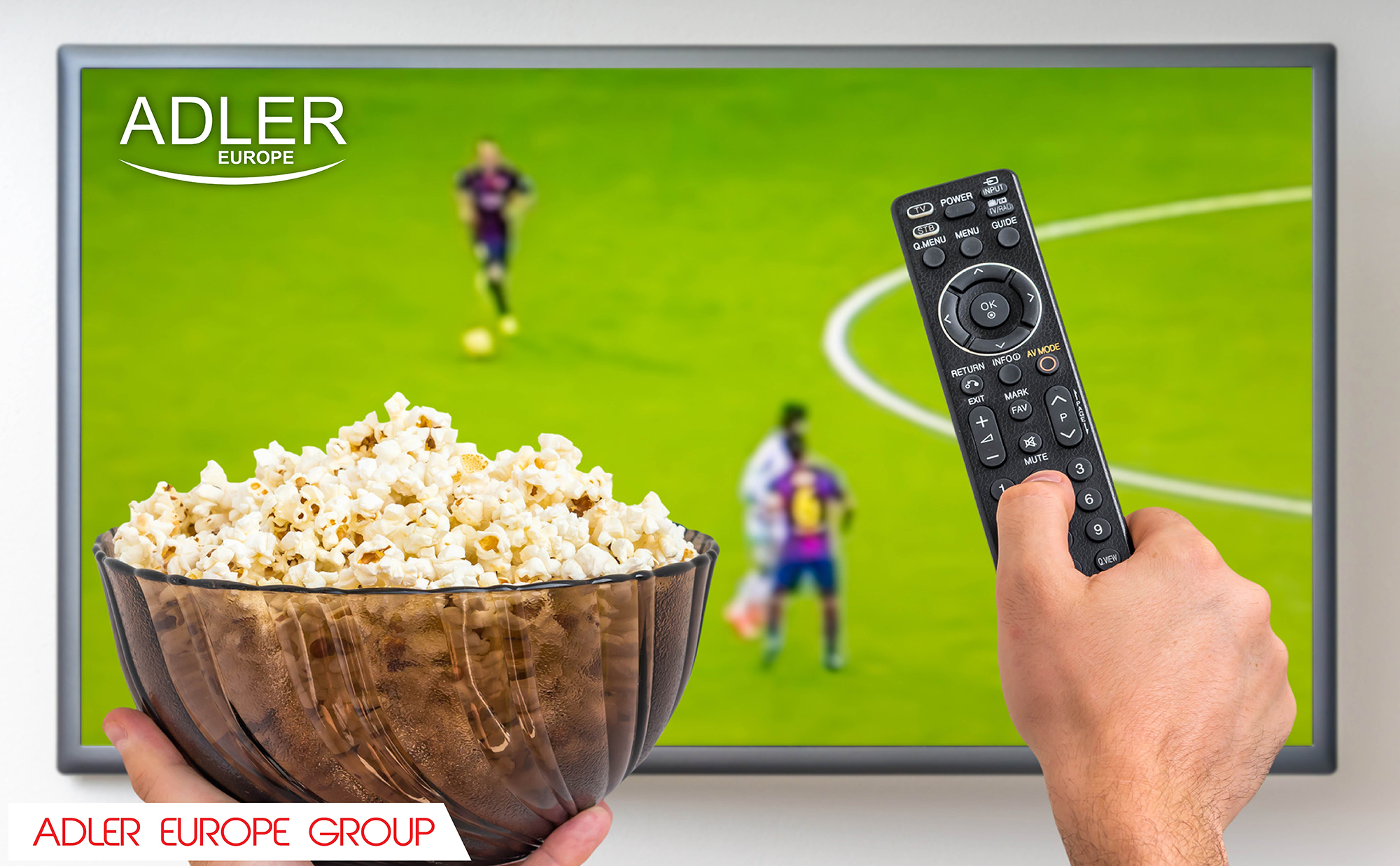 Eine Schüssel Popcorn und eine Fernbedienung vor einem Fernseher mit einem Fußballspiel.