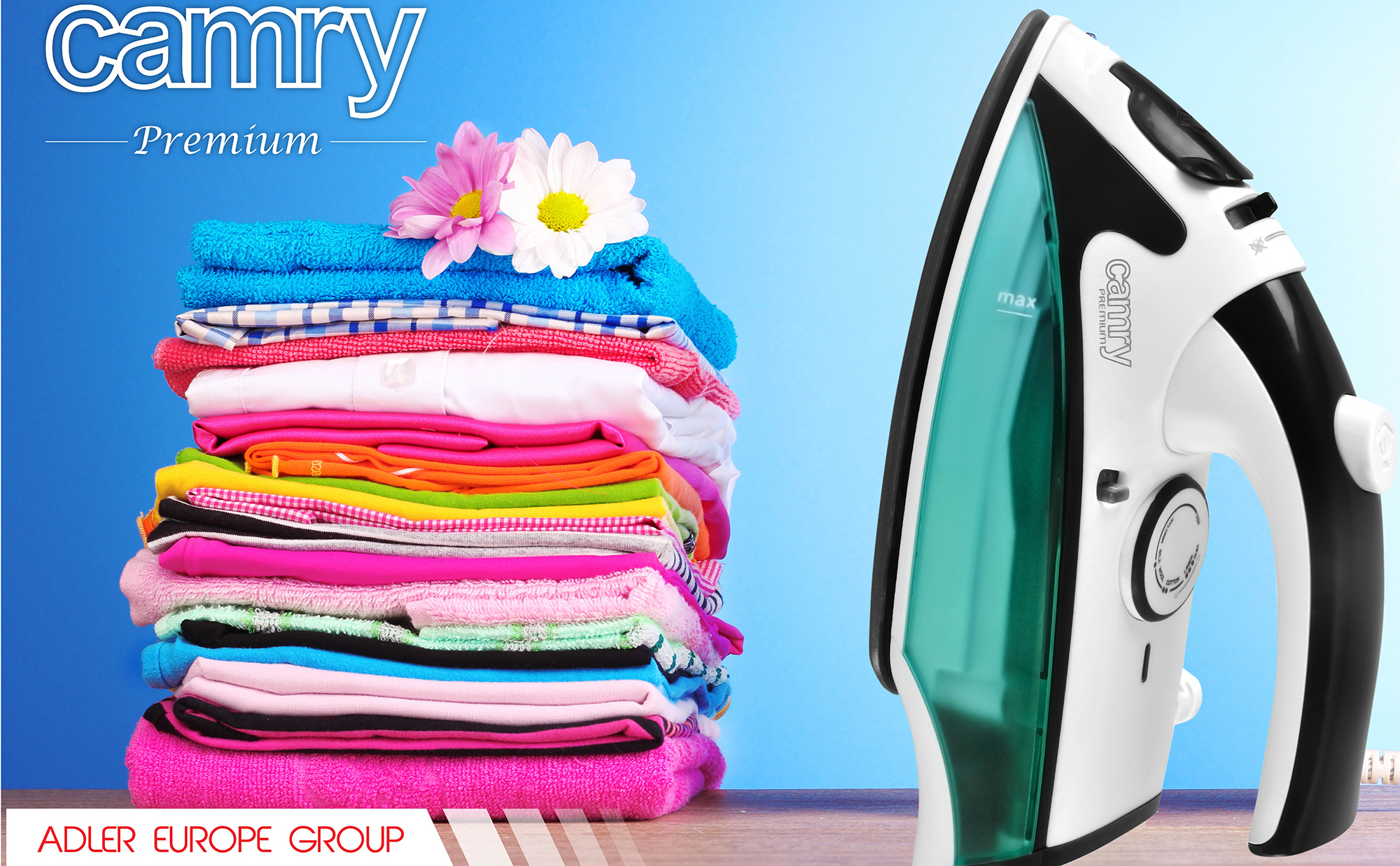 Żelazko i ręczniki na drewnianym stole. Żelazko jest czarne i zielone. Tło jest niebieskie.