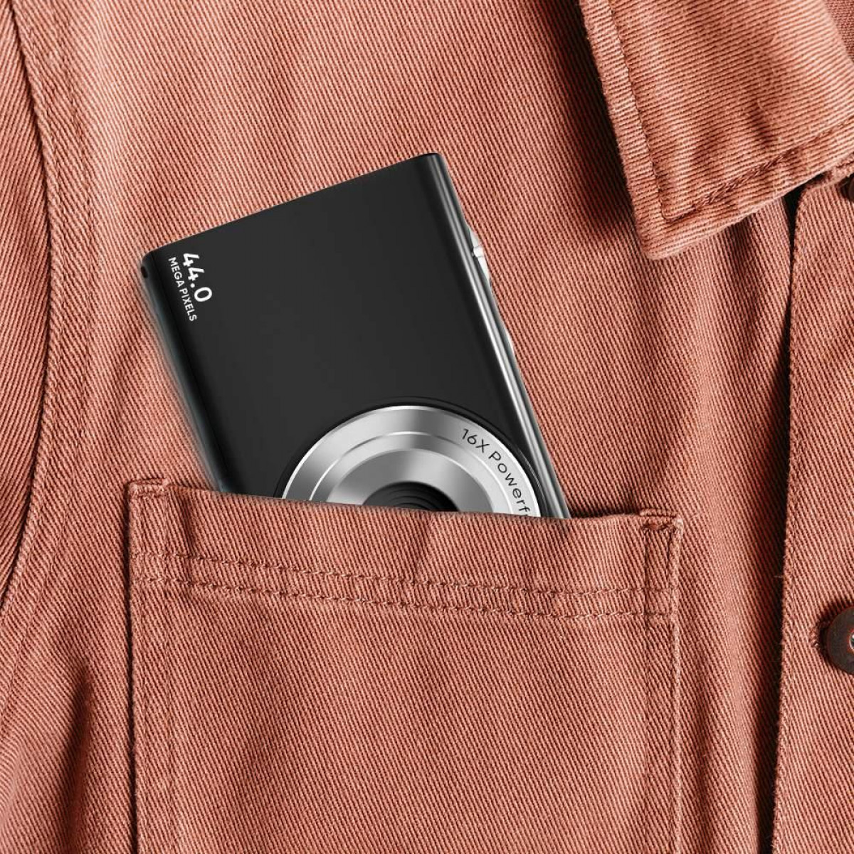 Czarny aparat w kieszeni. Pomarańczowa koszula. Aparat ma srebrny obiektyw.