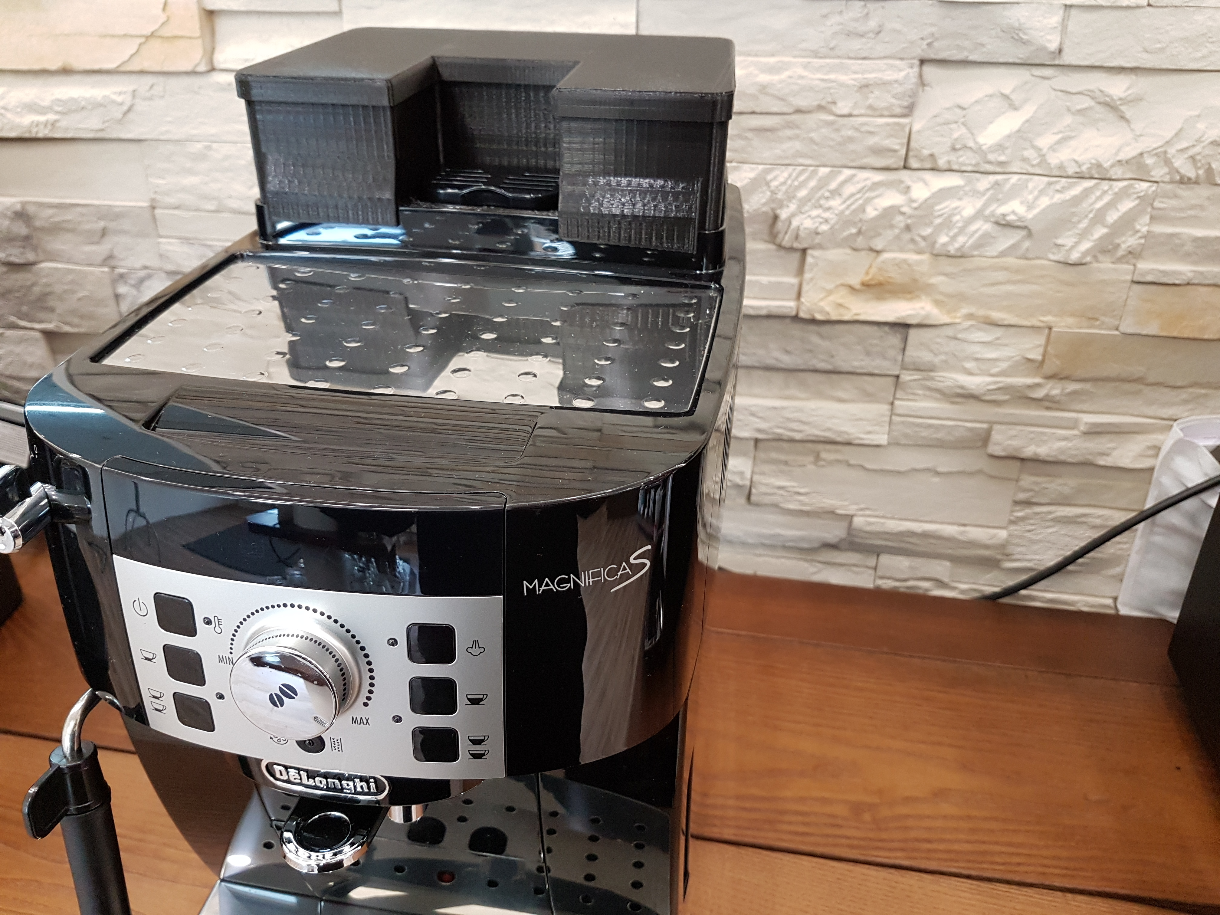 Schwarze Kaffeemaschine mit Wassertank auf Holzoberfläche.
