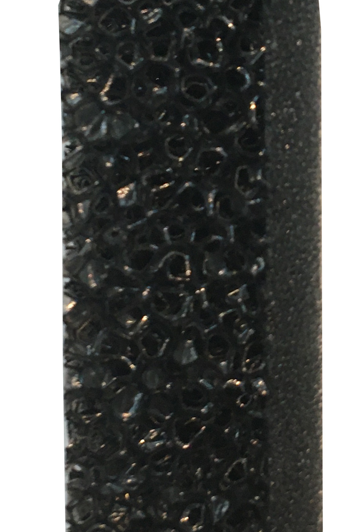 Nahaufnahme von schwarzem Material mit strukturierter Oberfläche und glattem schwarzem Rand.