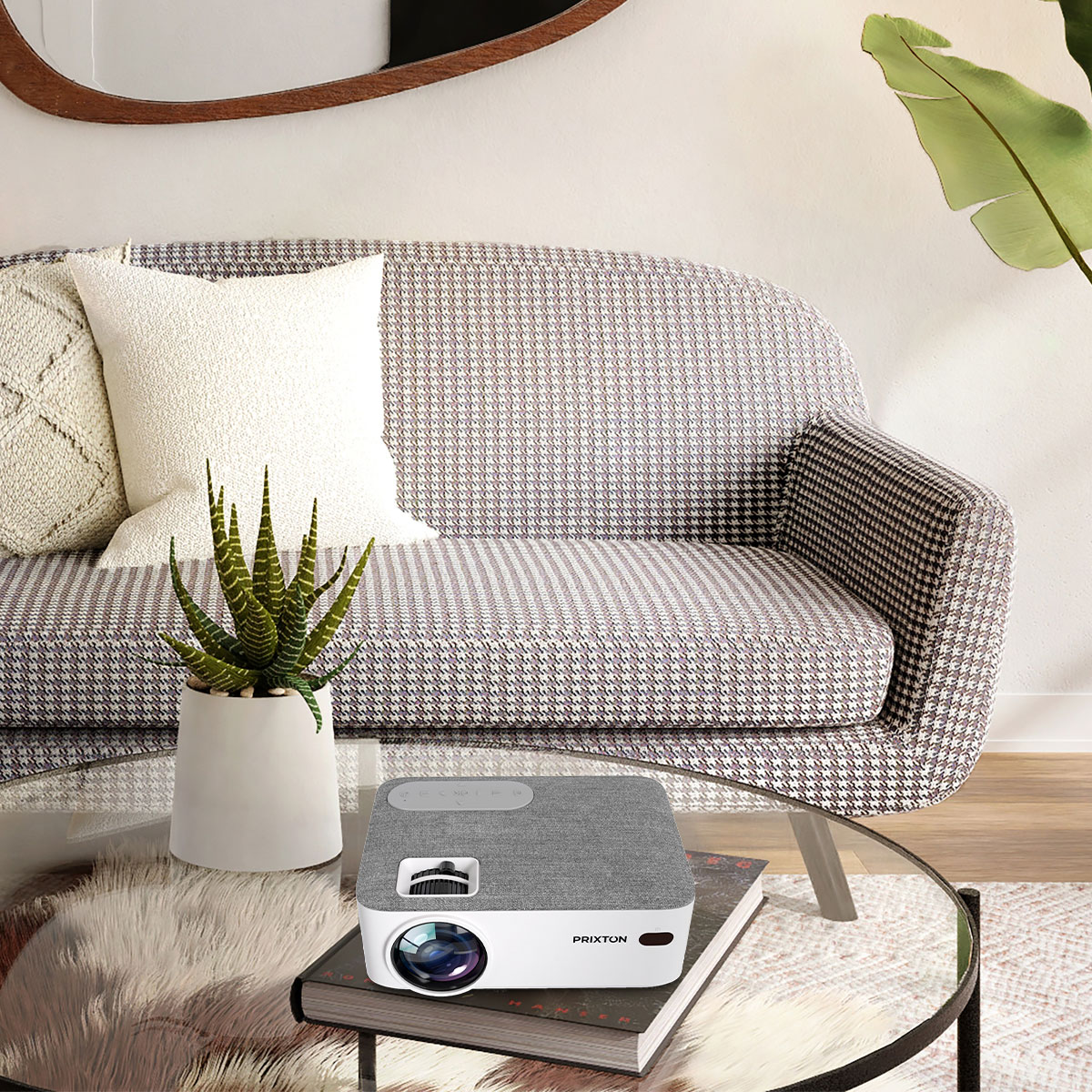 Projektor na stole z sofą i rośliną. Na podłodze dywan.