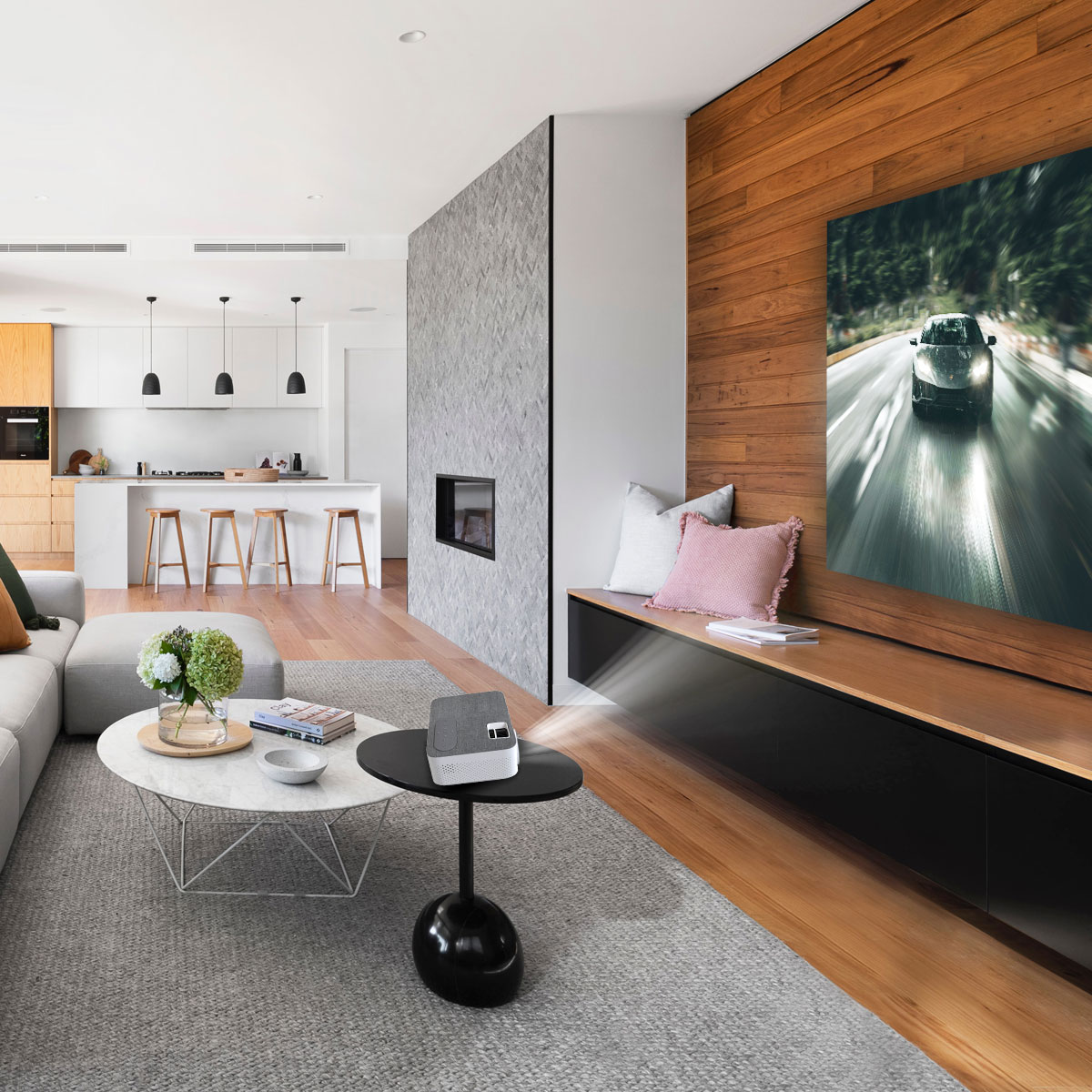 Nowoczesny salon z ekranem projekcyjnym pokazującym scenę wyścigu samochodowego. Pokój jest jasny.