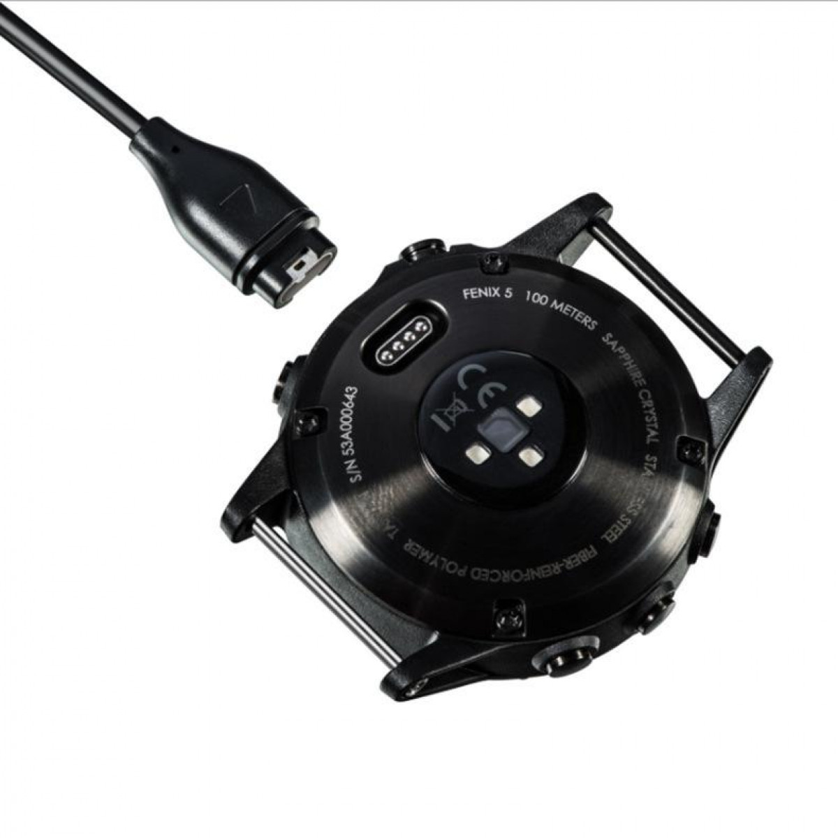 Czarny smartwatch z podłączonym kablem ładującym, tyłem do góry. Czarne tło.