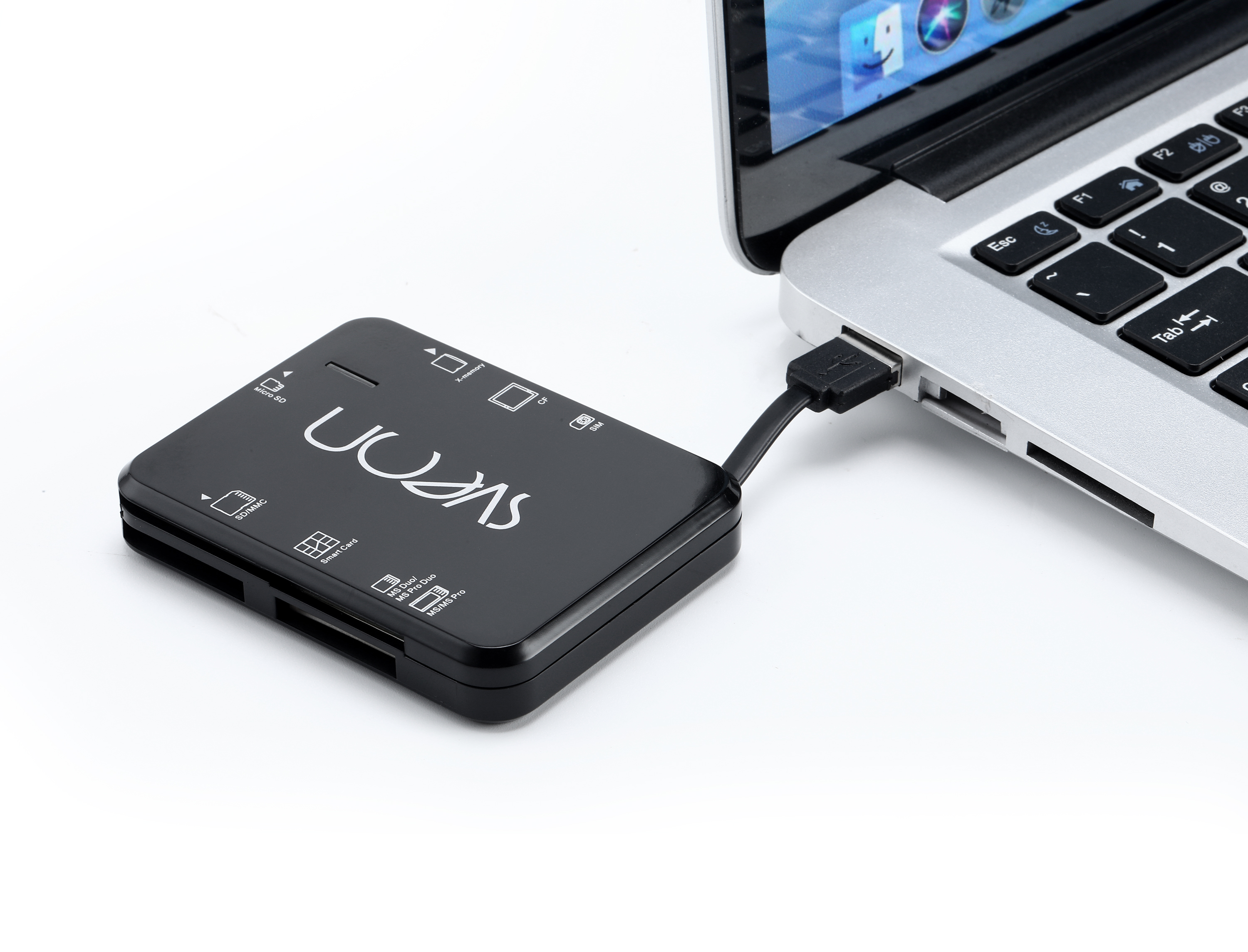 Un lector de tarjetas negro conectado a una computadora portátil a través de un cable USB. Fondo blanco.