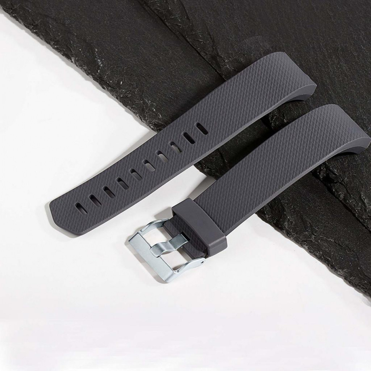 Zwei dunkelgraue Uhrenarmbänder auf hellgrauer Oberfläche.