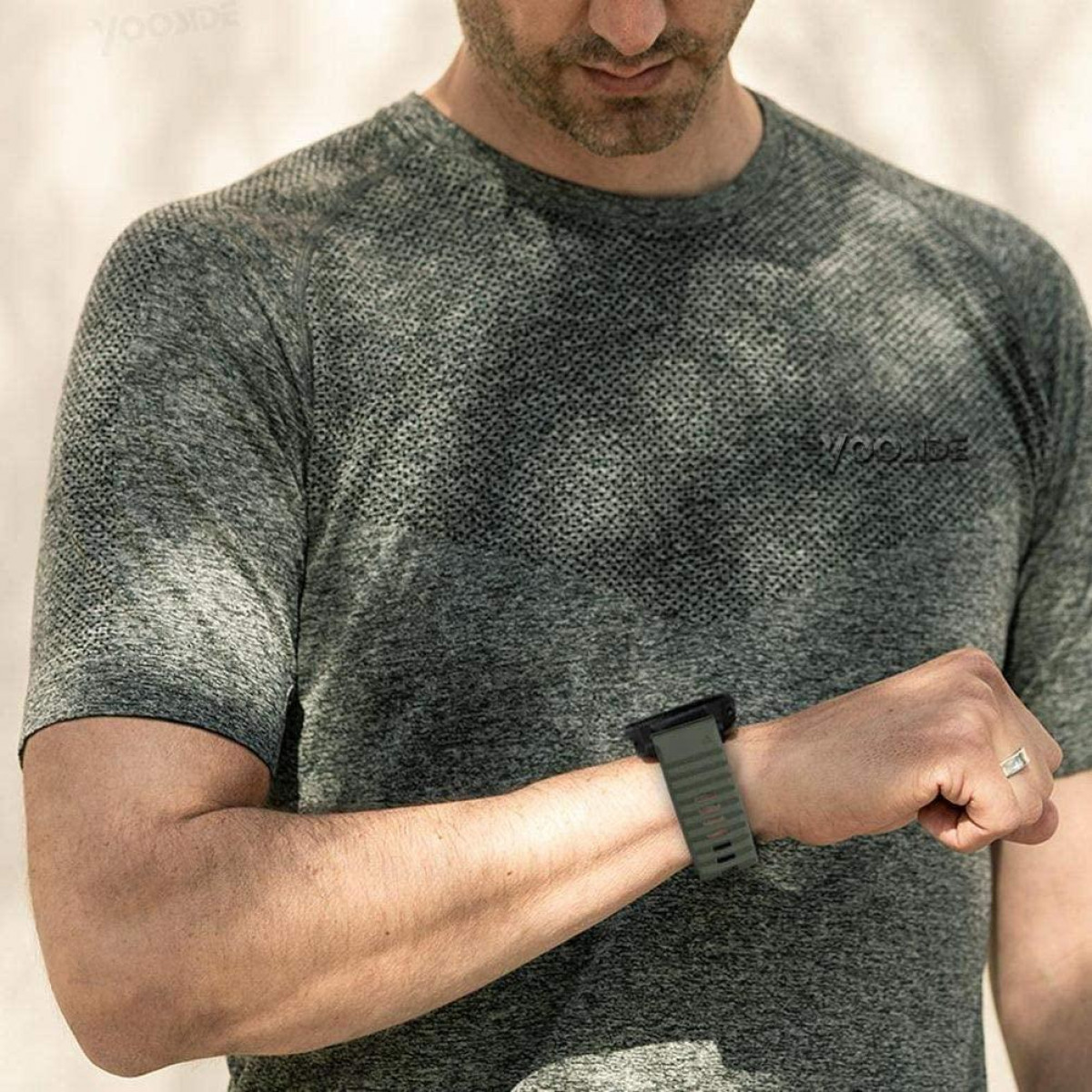 Mężczyzna w zielonej koszuli i zegarku z zielonym paskiem, pozuje na zewnątrz, słoneczny dzień.