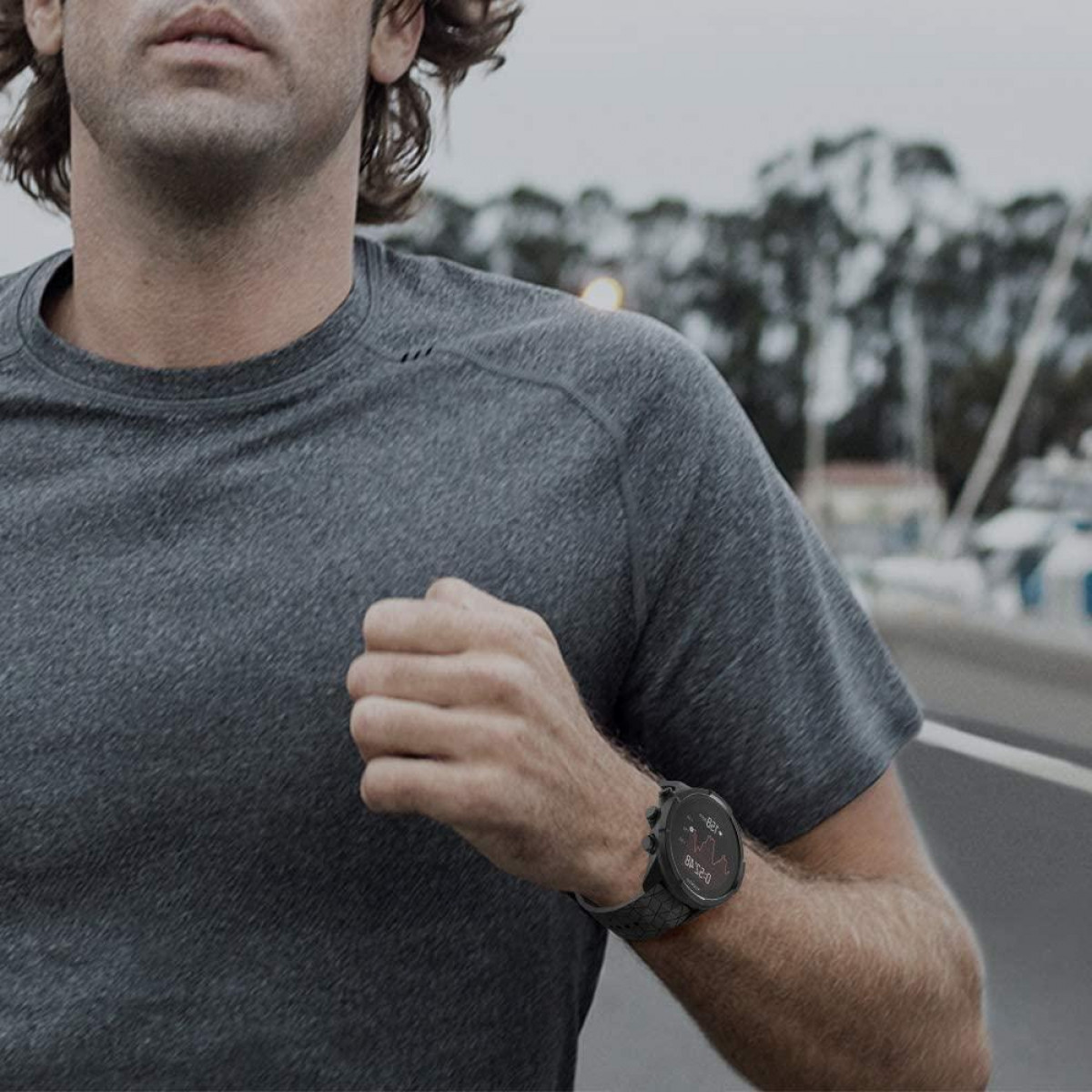 Un uomo che corre all'aperto mentre indossa un orologio sportivo al polso.